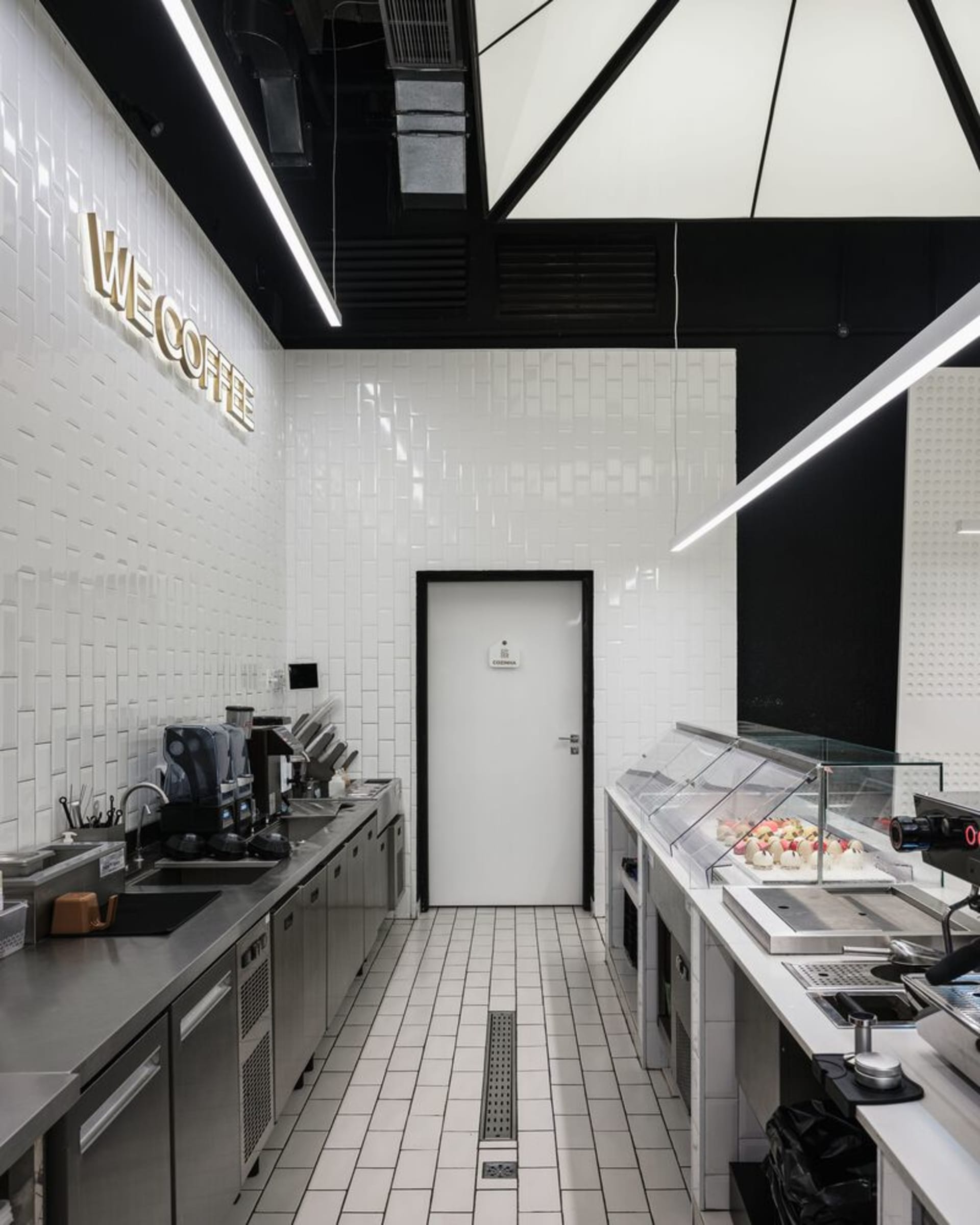 A well-lit coffee shop interior with modern appliances, cups, and bottles, conveying a welcoming and functional atmosphere