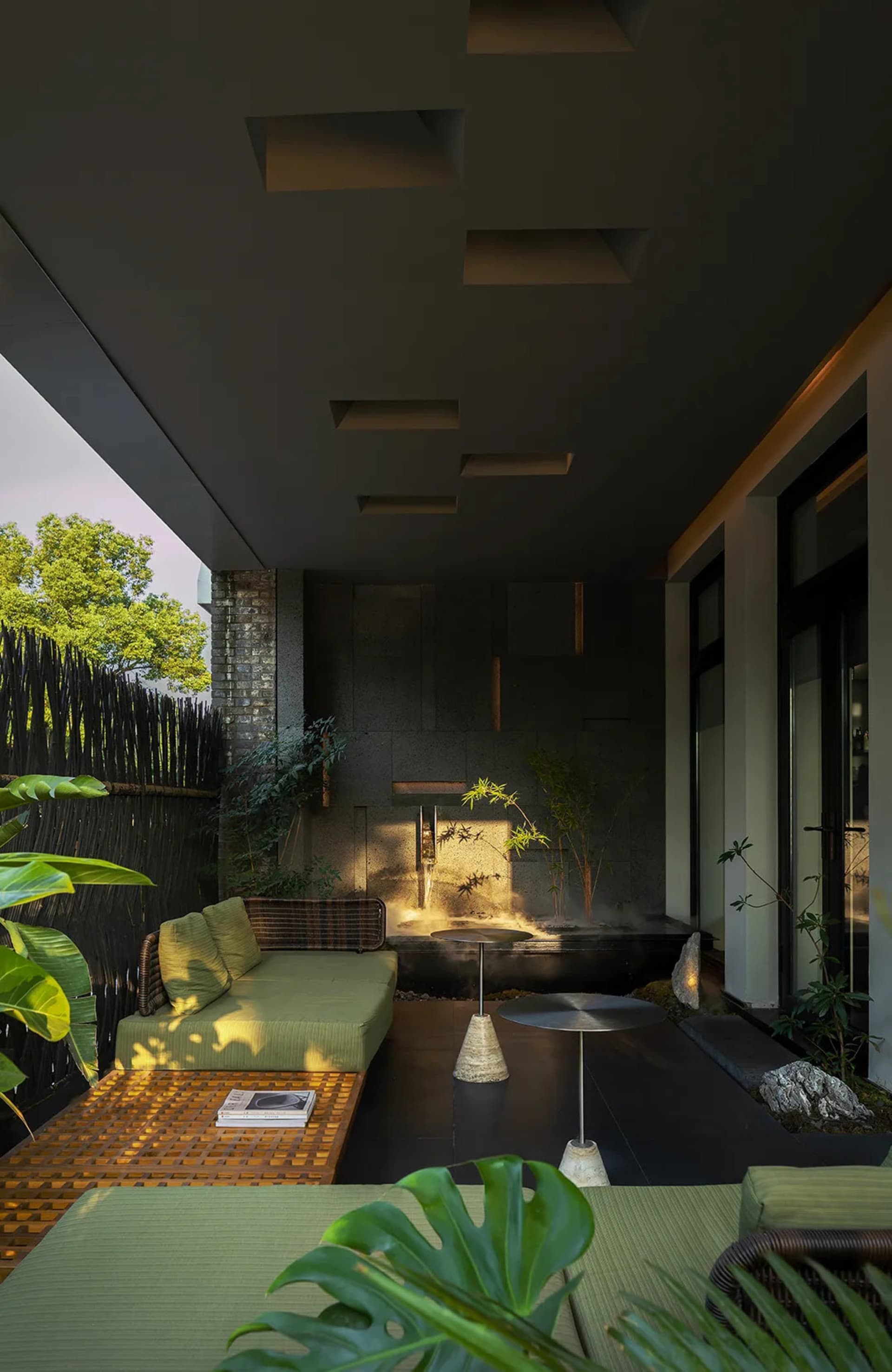 Modern living space with gray walls, black flooring, a couch, table, and sink, and two potted plants