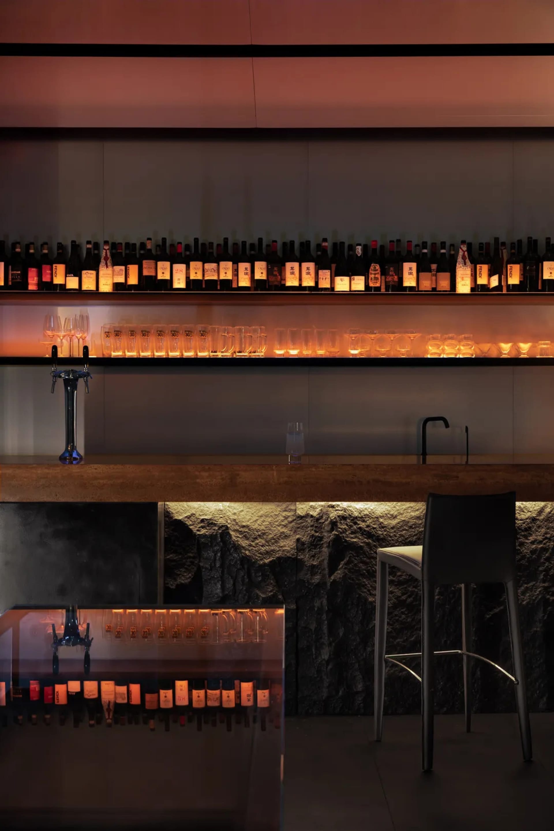 A modern bar area with a wine rack, wine glasses, and black and white elements creating a sophisticated atmosphere