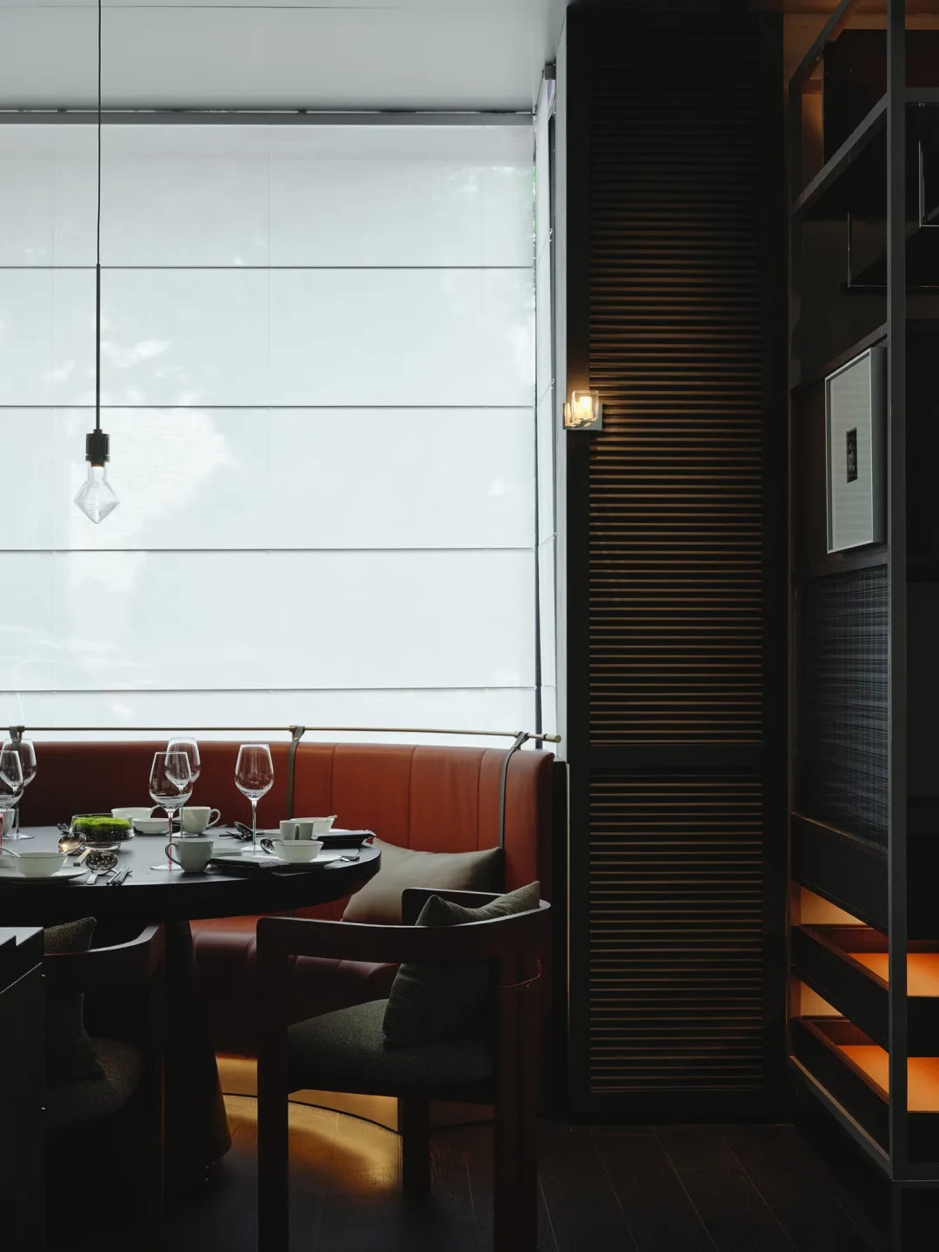 Sophisticated dining area with a large window, multiple chairs, and wine glasses on a dining table