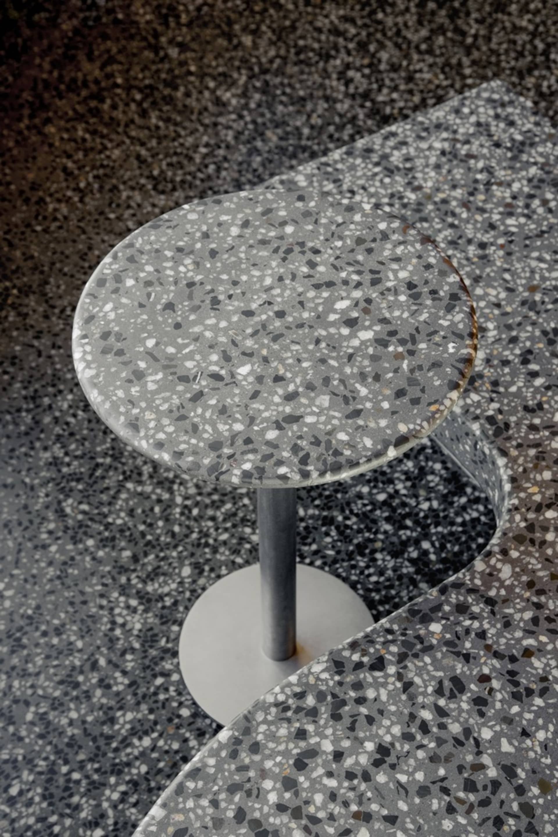 Modern dining space with a round table and chair on a black and white checkered tile floor, suggesting a stylish and possibly restaurant or cafe setting