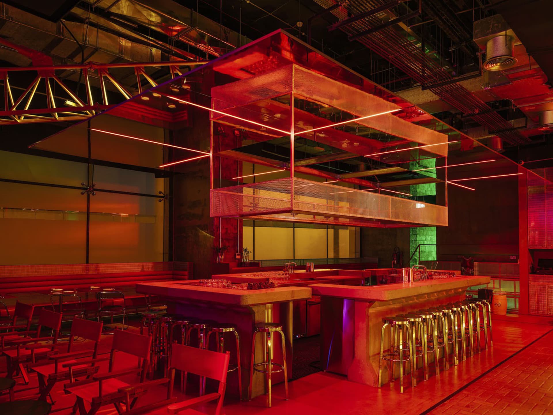 Modern industrial kitchen with red walls, a wooden countertop, and multiple chairs around the dining area