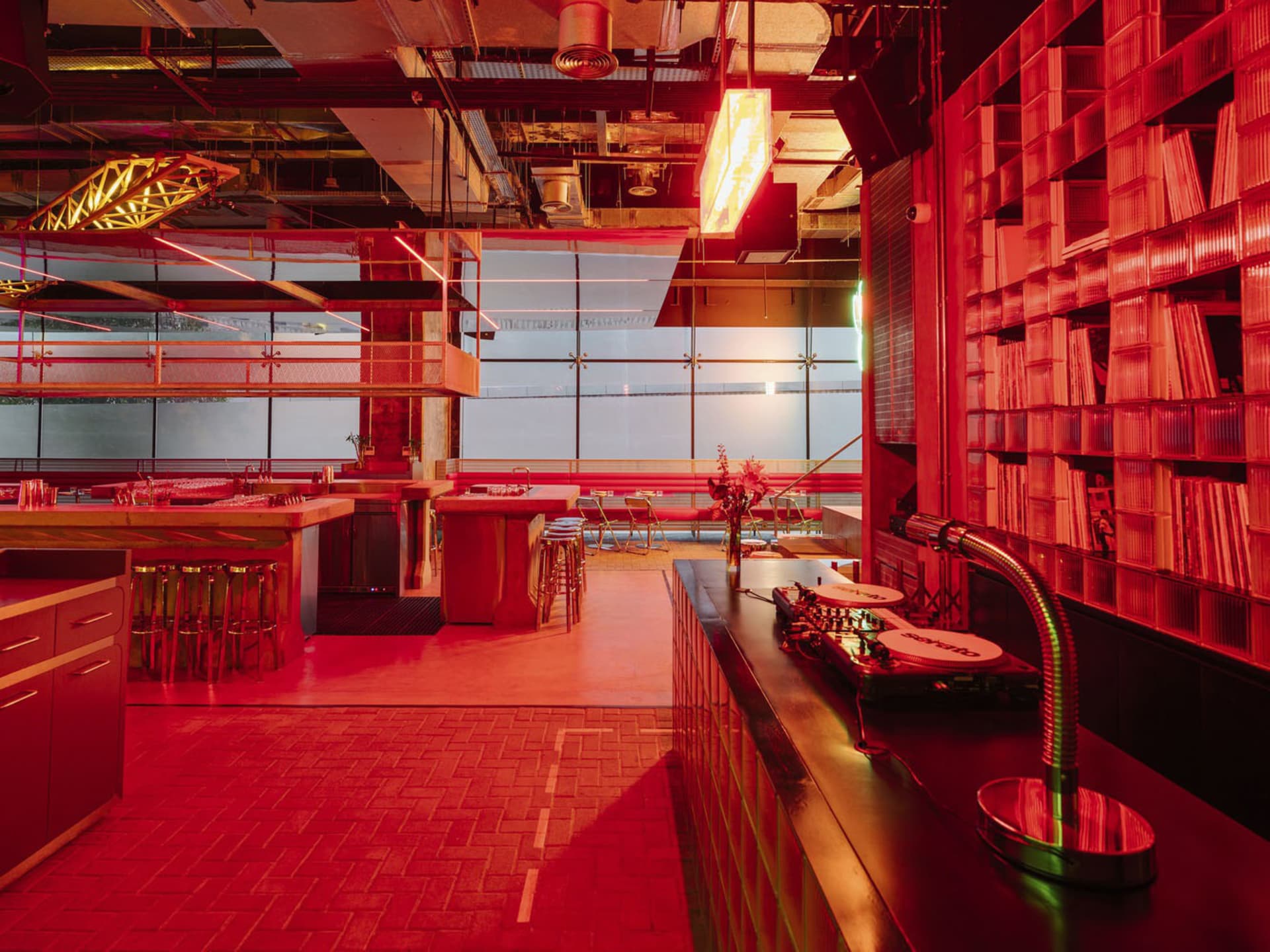 A modern restaurant interior with red walls, a dining table, and comfortable seating for patrons, featuring a warm and inviting atmosphere