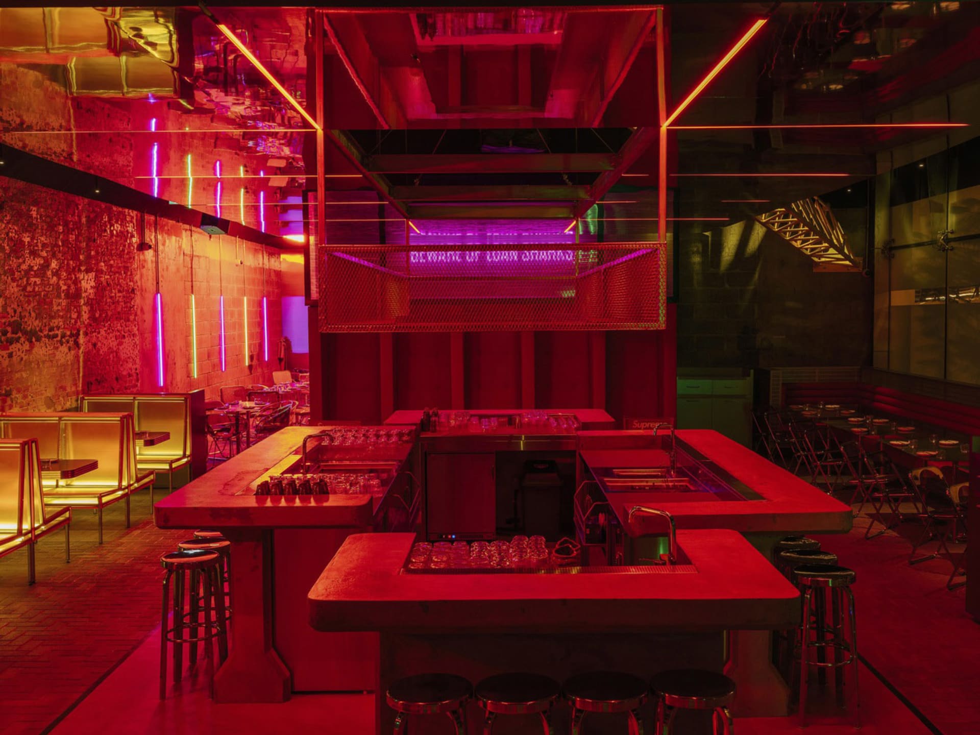 A lively bar area with a long red counter and stools, surrounded by chairs in a warm and inviting atmosphere