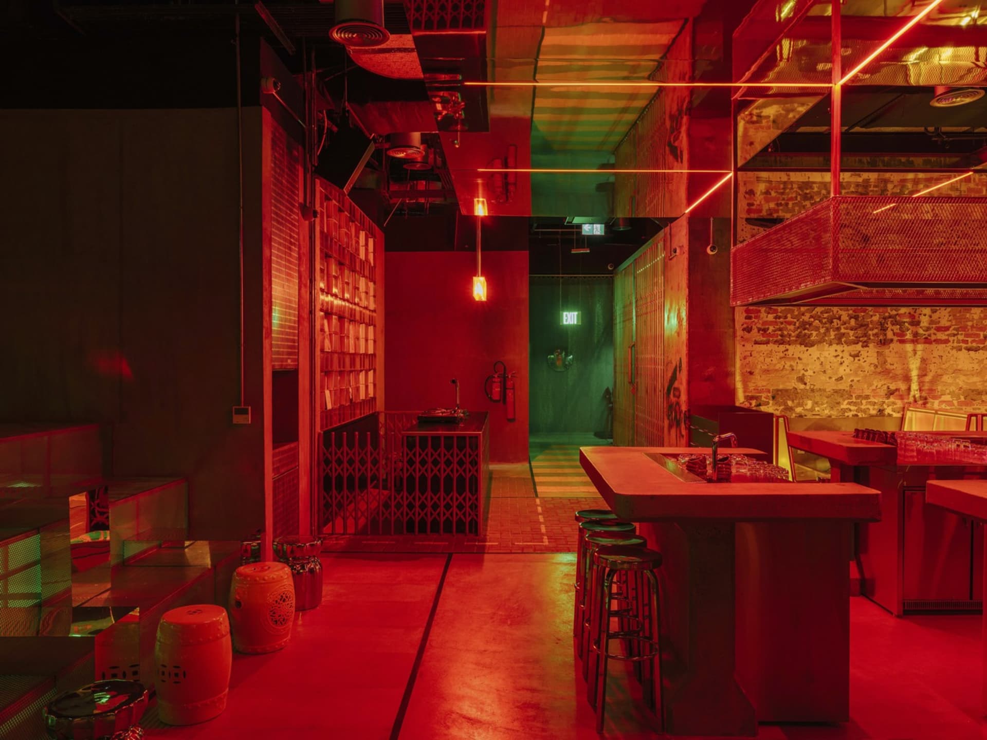 A futuristic bar area with red lighting, green walls, and several dining tables and chairs
