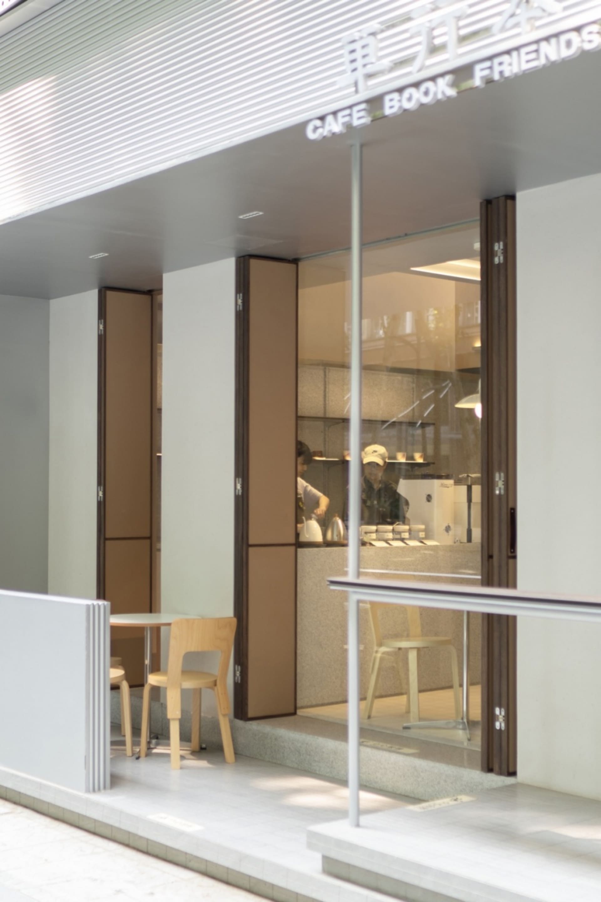 A modern dining area with three chairs and two tables, featuring a warm atmosphere with dim lighting and a combination of white and brown tones on the walls