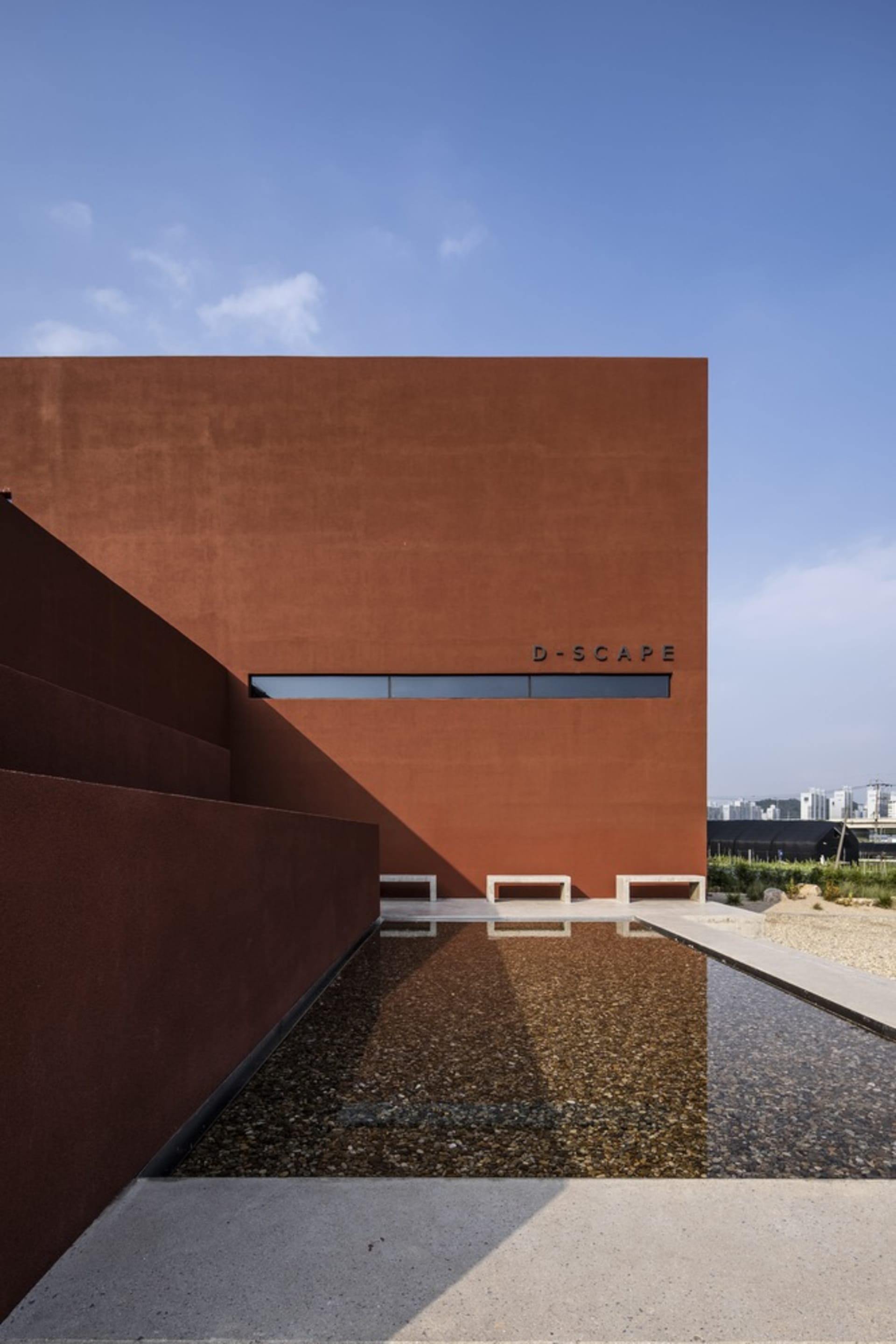 A modern building with a red brick exterior and a large window on its side