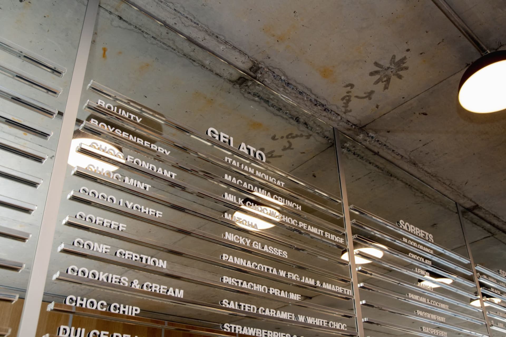 A colorful menu board displaying gelato flavors, cookies, and fresh strawberries, with text and images highlighting each dish