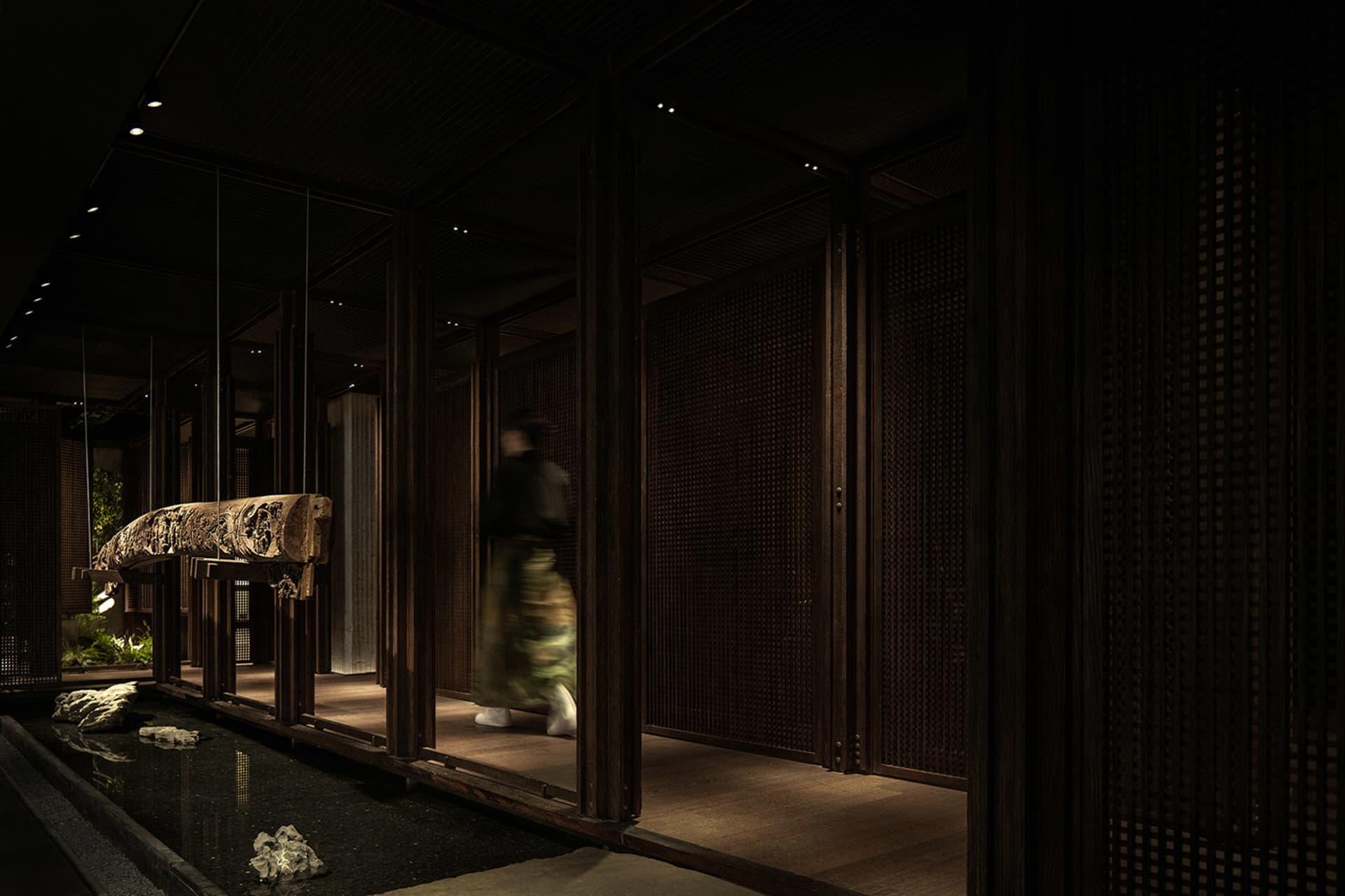 A woman walks down a wooden hallway with two doors, surrounded by classic architectural details