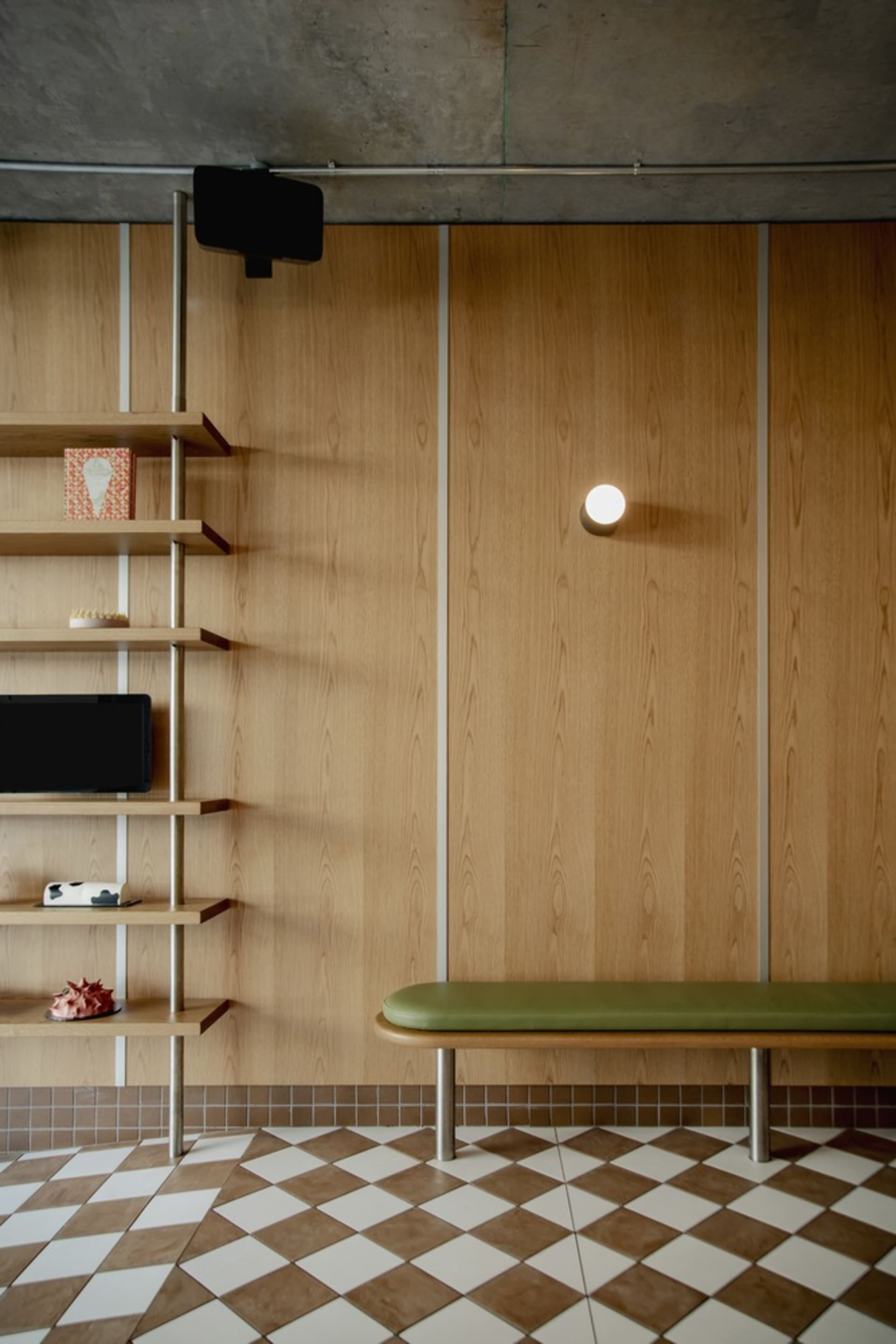 Cozy modern study with wooden walls and floors, featuring two bookshelves, a bench, and a mounted TV, creating a functional and inviting space