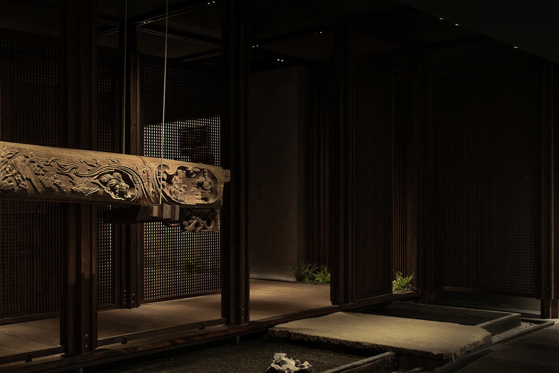 Warm and inviting room with wooden walls and floors, a large wooden table, and potted plants, featuring traditional Asian design elements