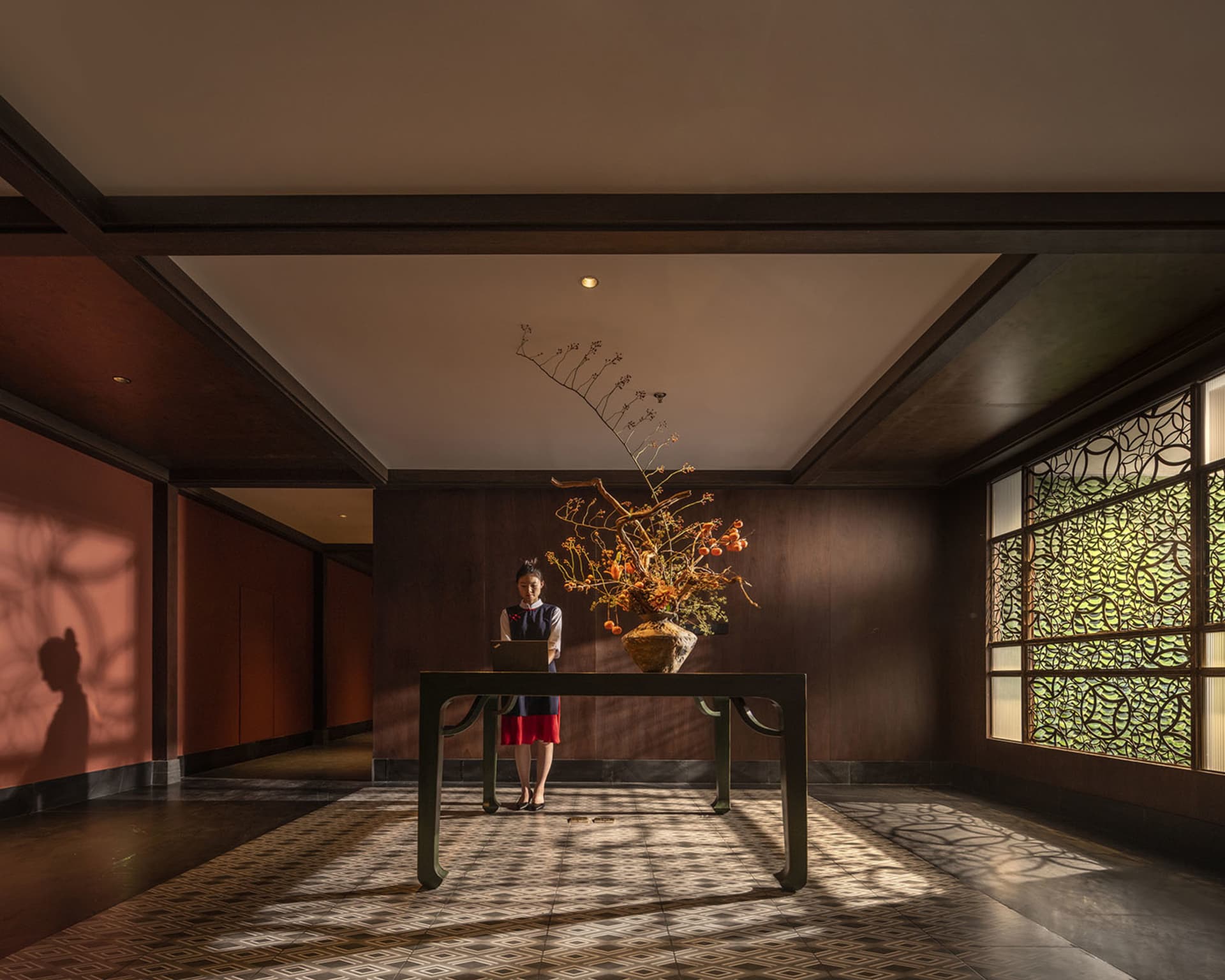 A cozy lobby with a wooden floor, a dining table, chairs, and a vase, creating a comfortable and inviting atmosphere