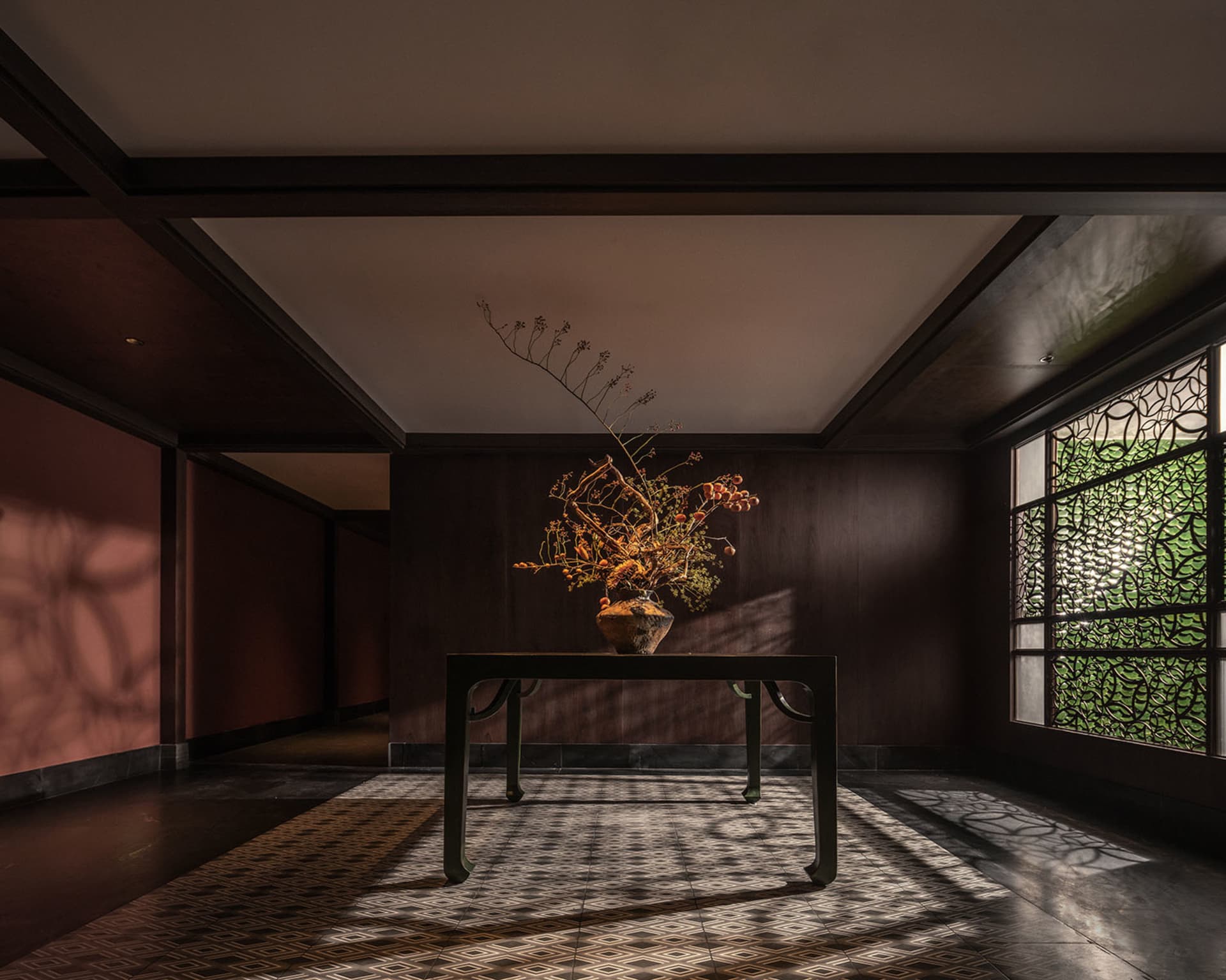 明亮室內空間，設有木桌、花瓶插花與盆栽，搭配木質地板與窗邊自然光線