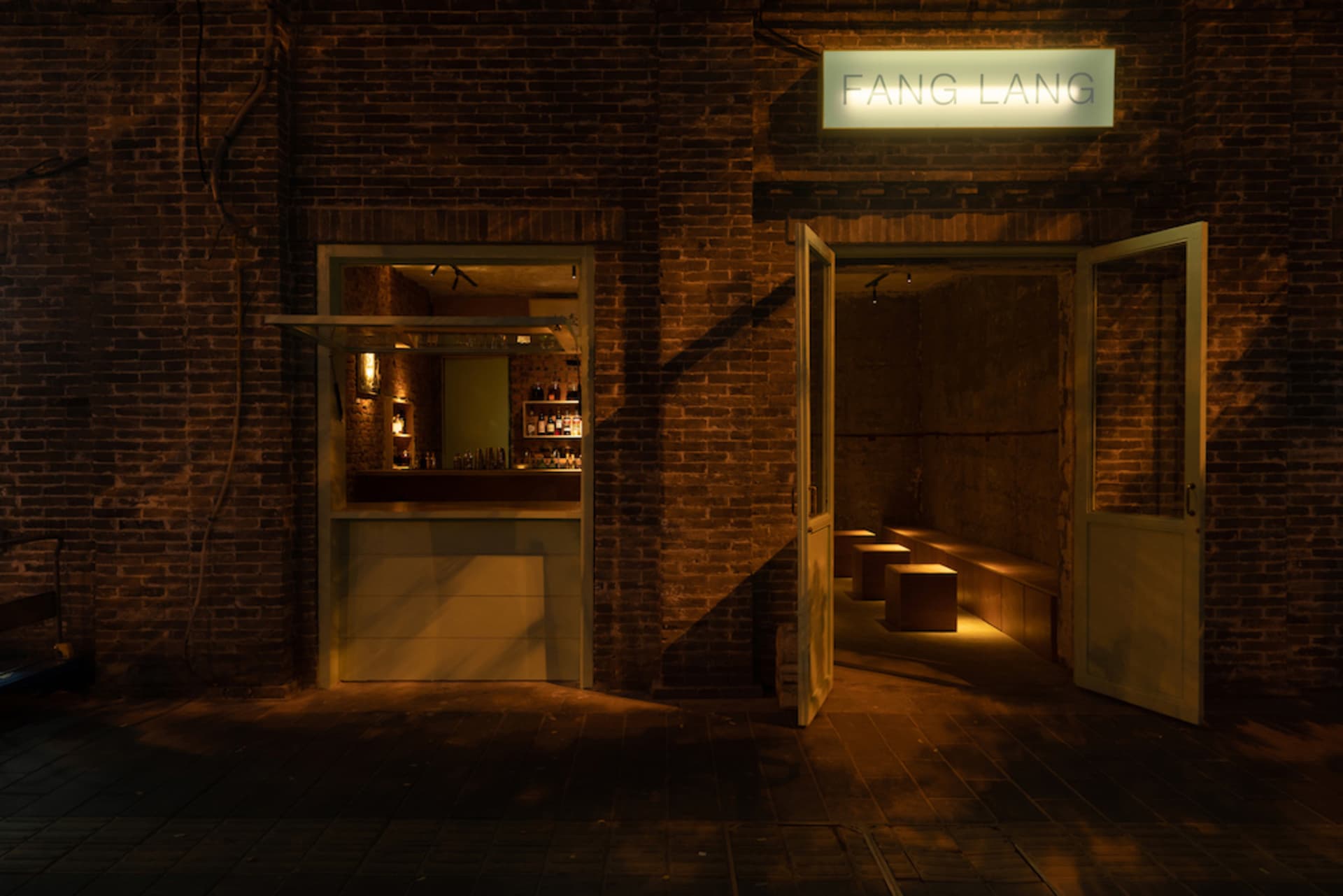 Cozy Asian restaurant with a brick wall, wooden door, and bottles on display, blending modern and traditional design elements