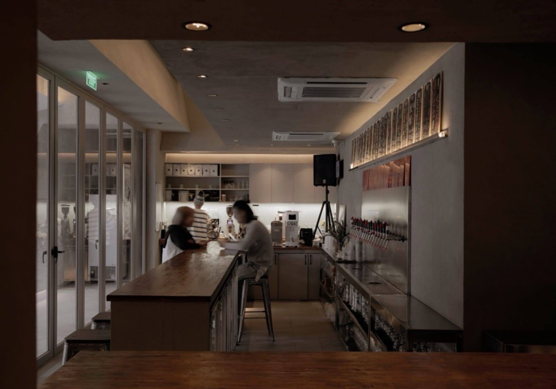 A casual restaurant bar area with patrons enjoying their time together, featuring a counter with bottles, cups, and bowls, and a refrigerator in the background