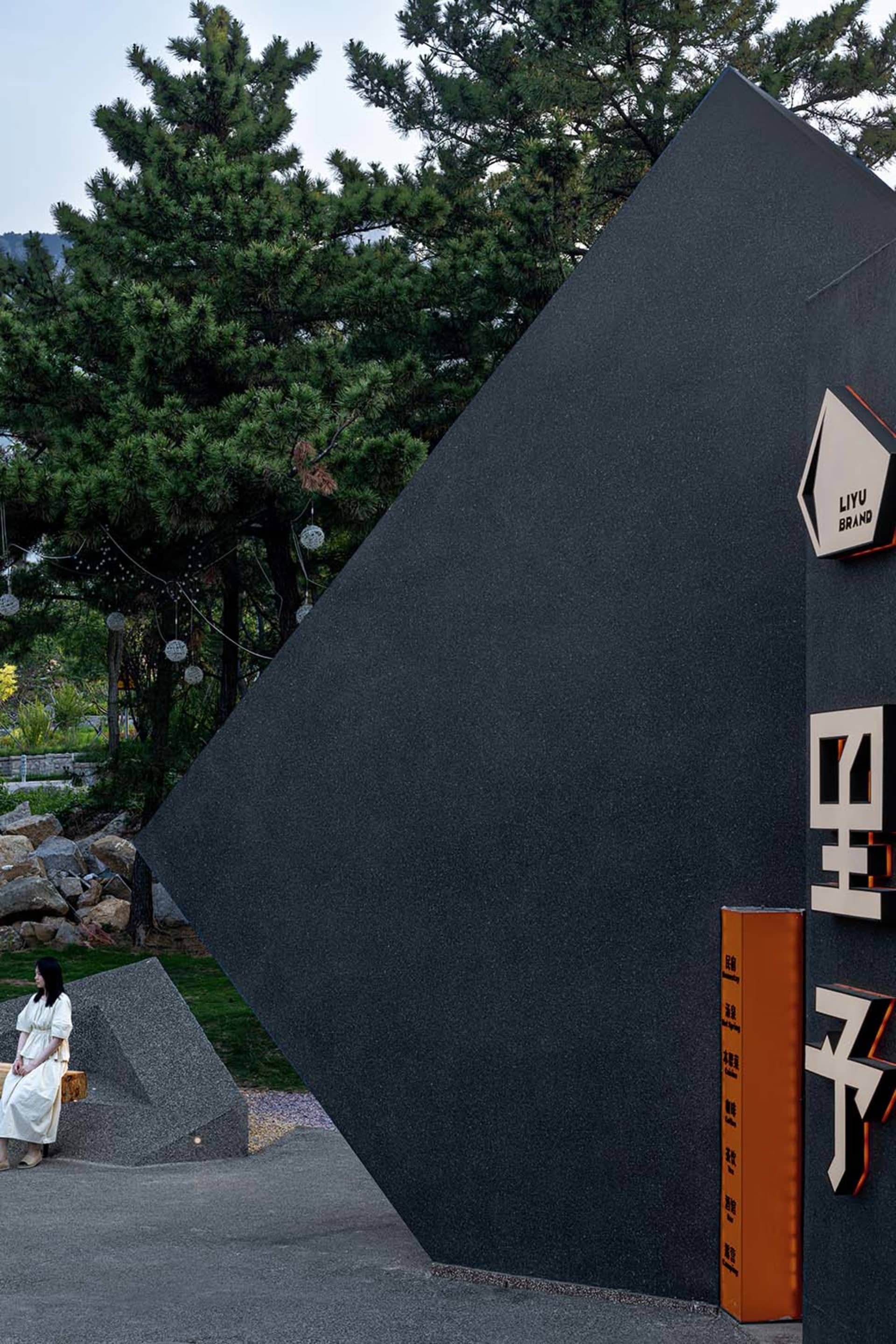 Modern black building with a large triangular shape on its side, two women standing in front, giving a calm and inviting atmosphere