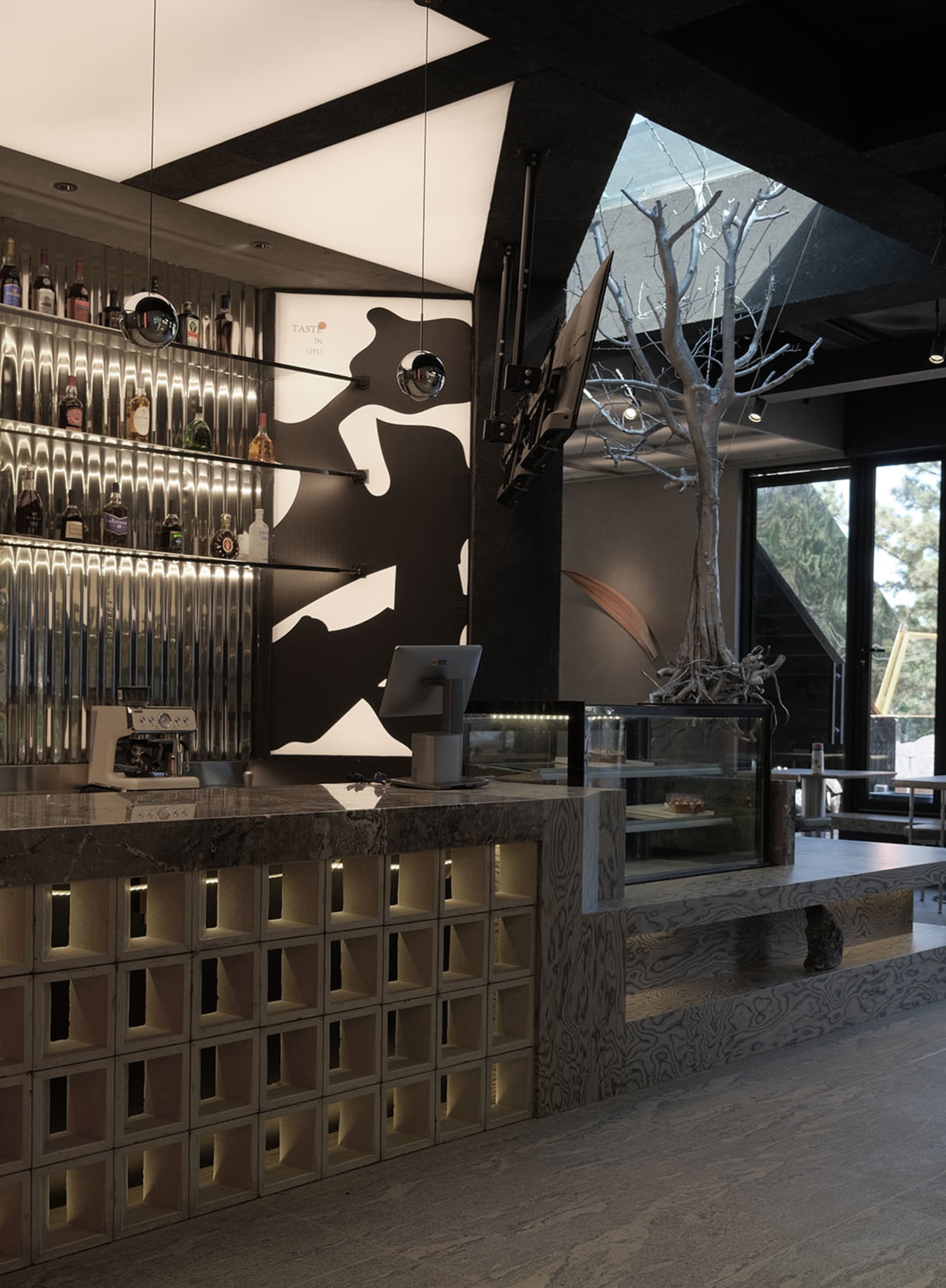 A casual bar area with a counter featuring a coffee maker and TV, surrounded by bottles and chairs for seating