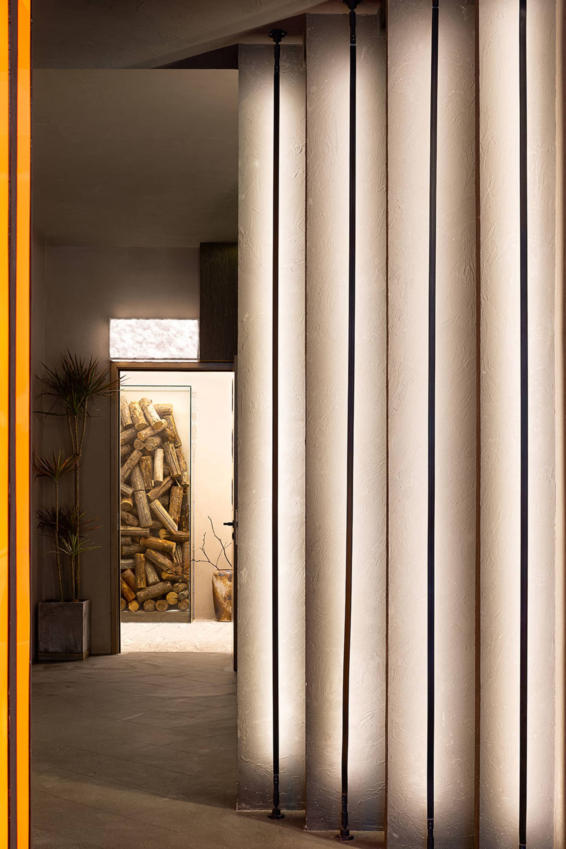 Traditional hallway with wooden surfaces, two potted plants, and a doorway leading to another room