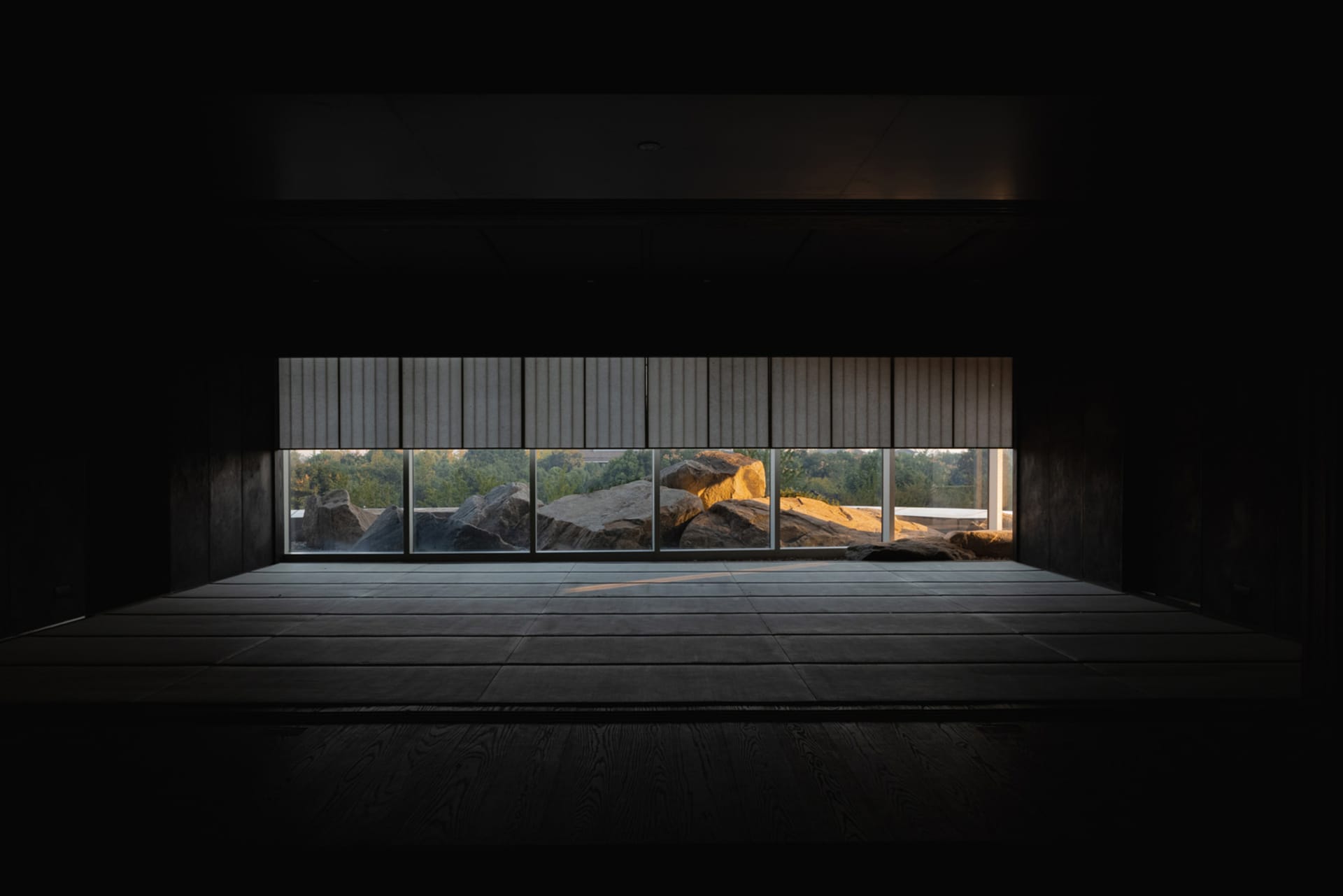 Empty living room with large windows offering a view of rocks outside, receiving natural light