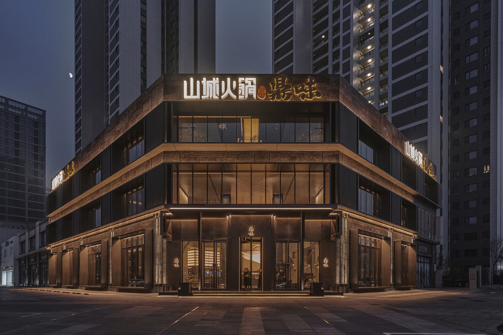 Modern Asian building exterior at night with a large sign on its facade, set against a cityscape