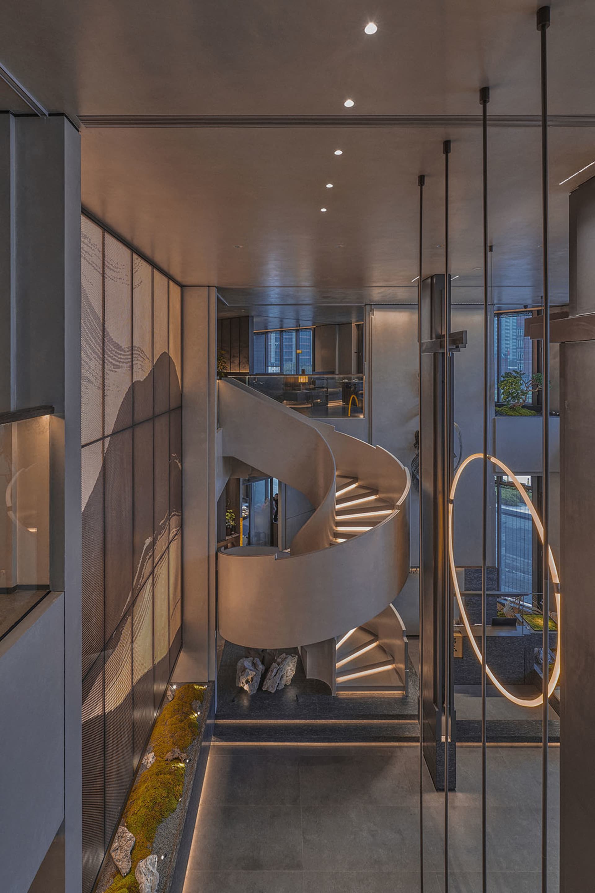 A modern spiral staircase with a metal railing and concrete steps, surrounded by walls with artwork and a contemporary atmosphere