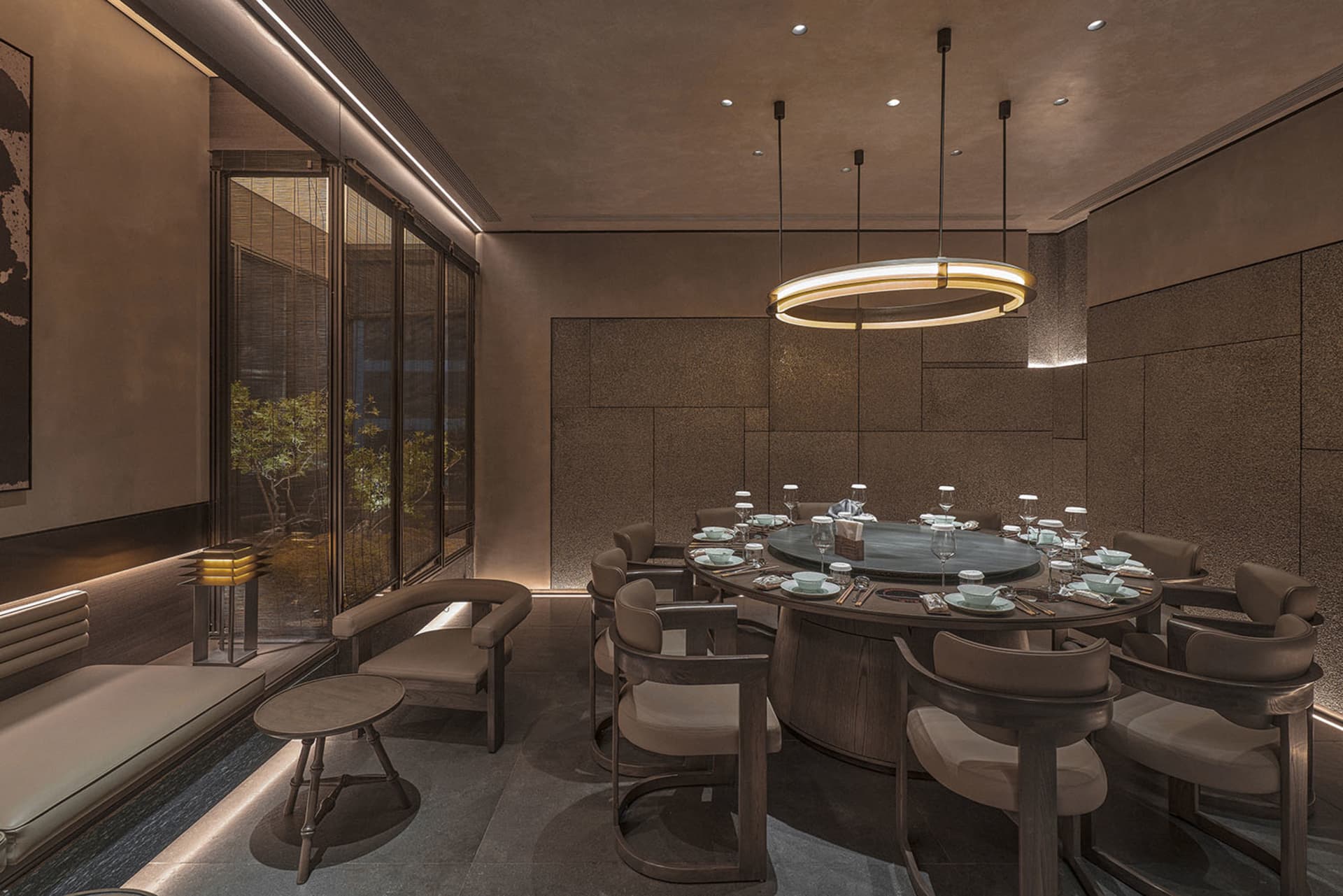 A calm and inviting dining area with a round table, chairs, and a mix of wood and stone elements