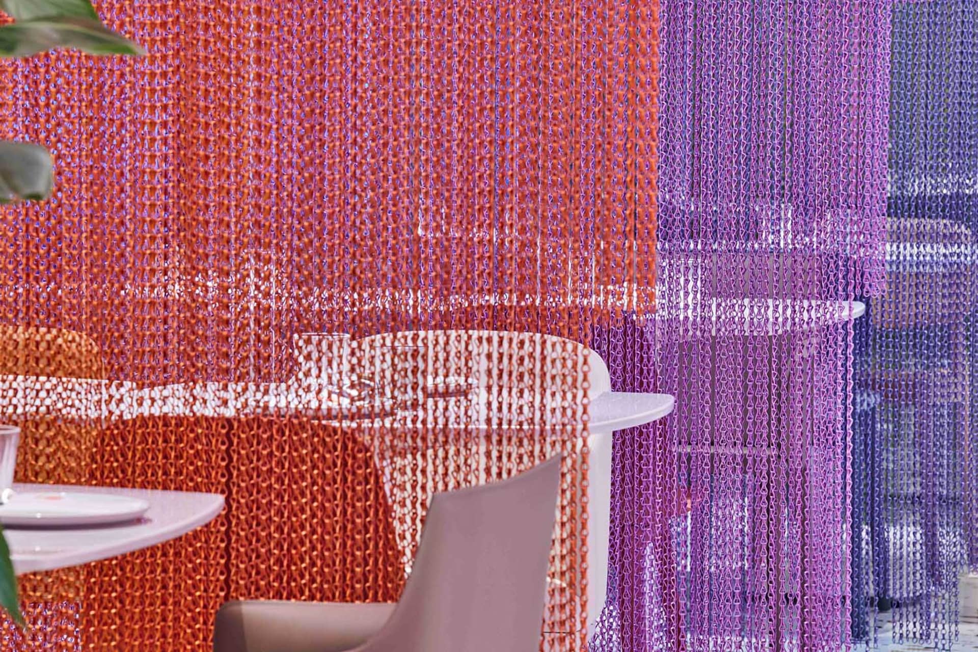 A modern restaurant dining area with a purple and orange color scheme, featuring two chairs and a dining table surrounded by chairs, creating an inviting and comfortable atmosphere