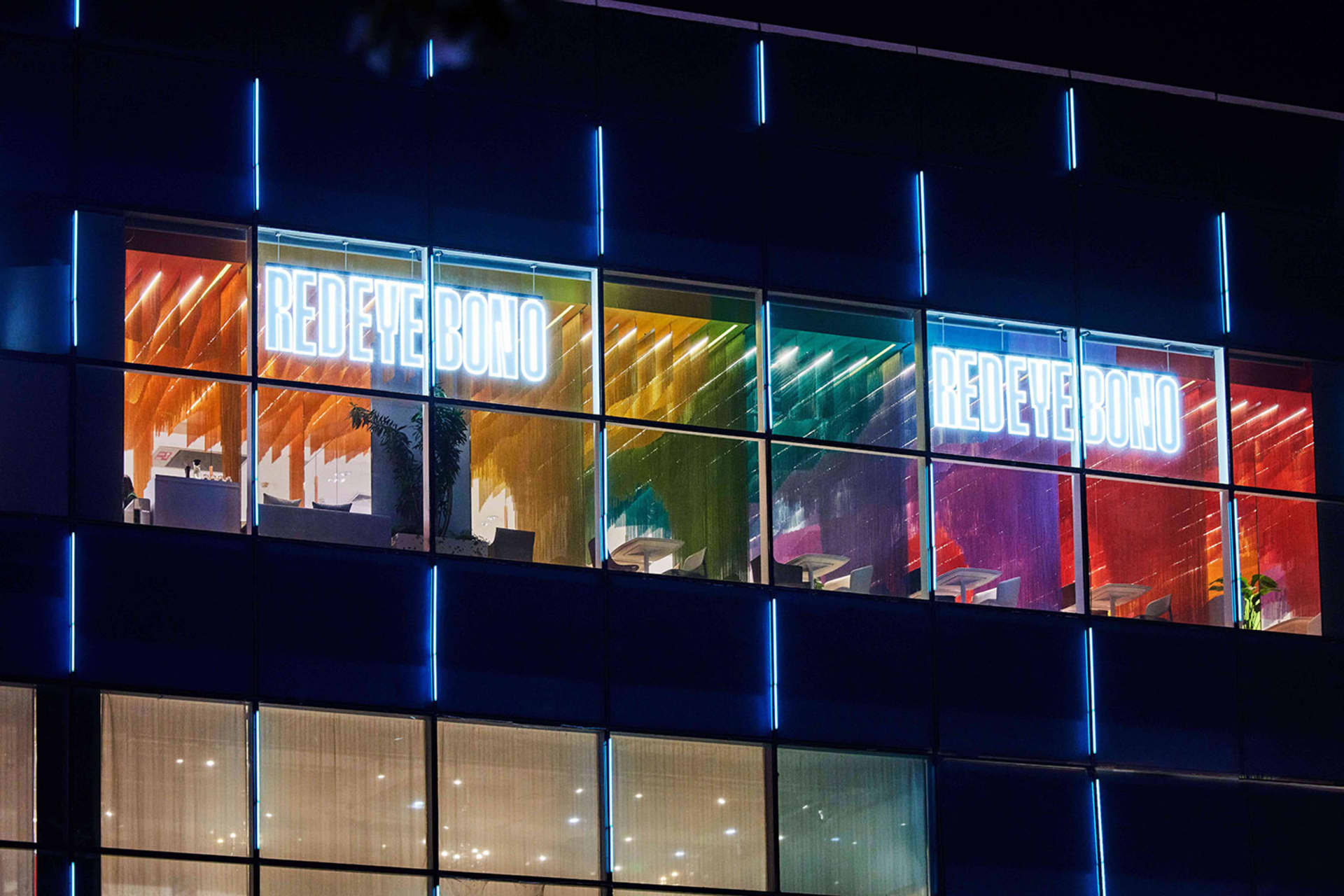 Bright office space with a large glass window, neon sign, and modern furniture