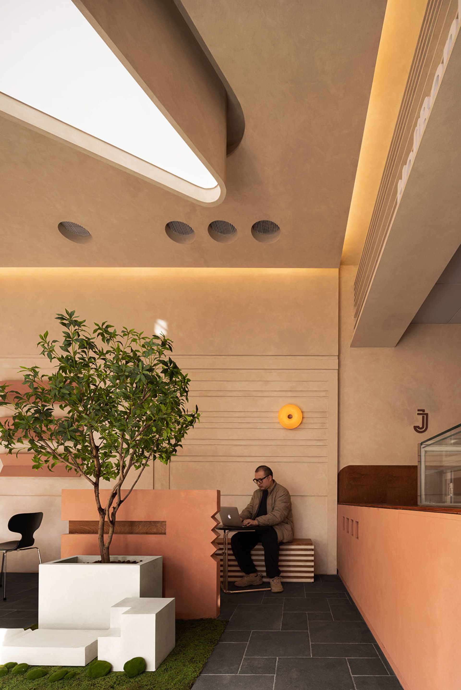A comfortable home office with a bench and chairs, surrounded by potted plants and natural light