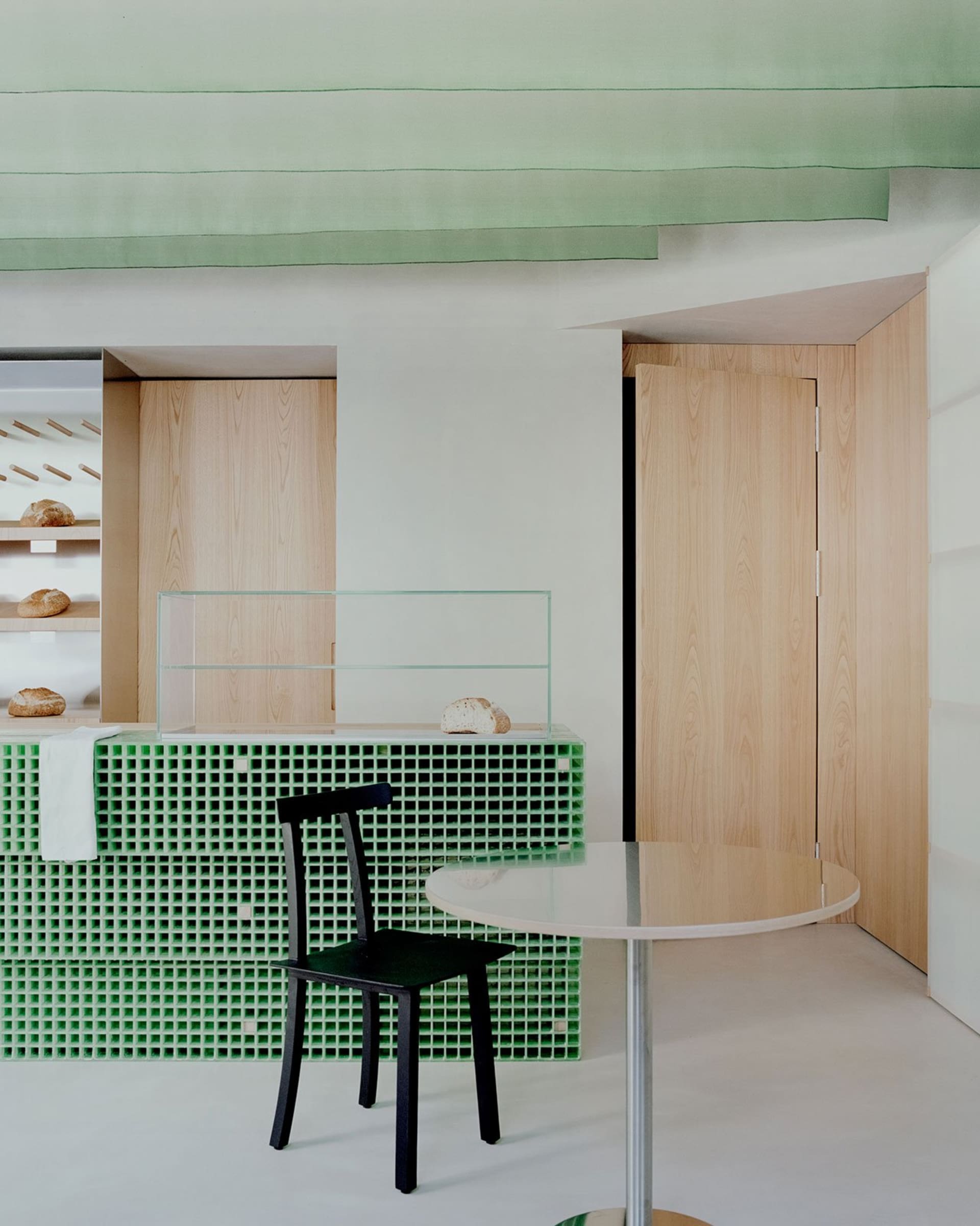 Dining area with a glass table surrounded by chairs, green tile walls, and a countertop