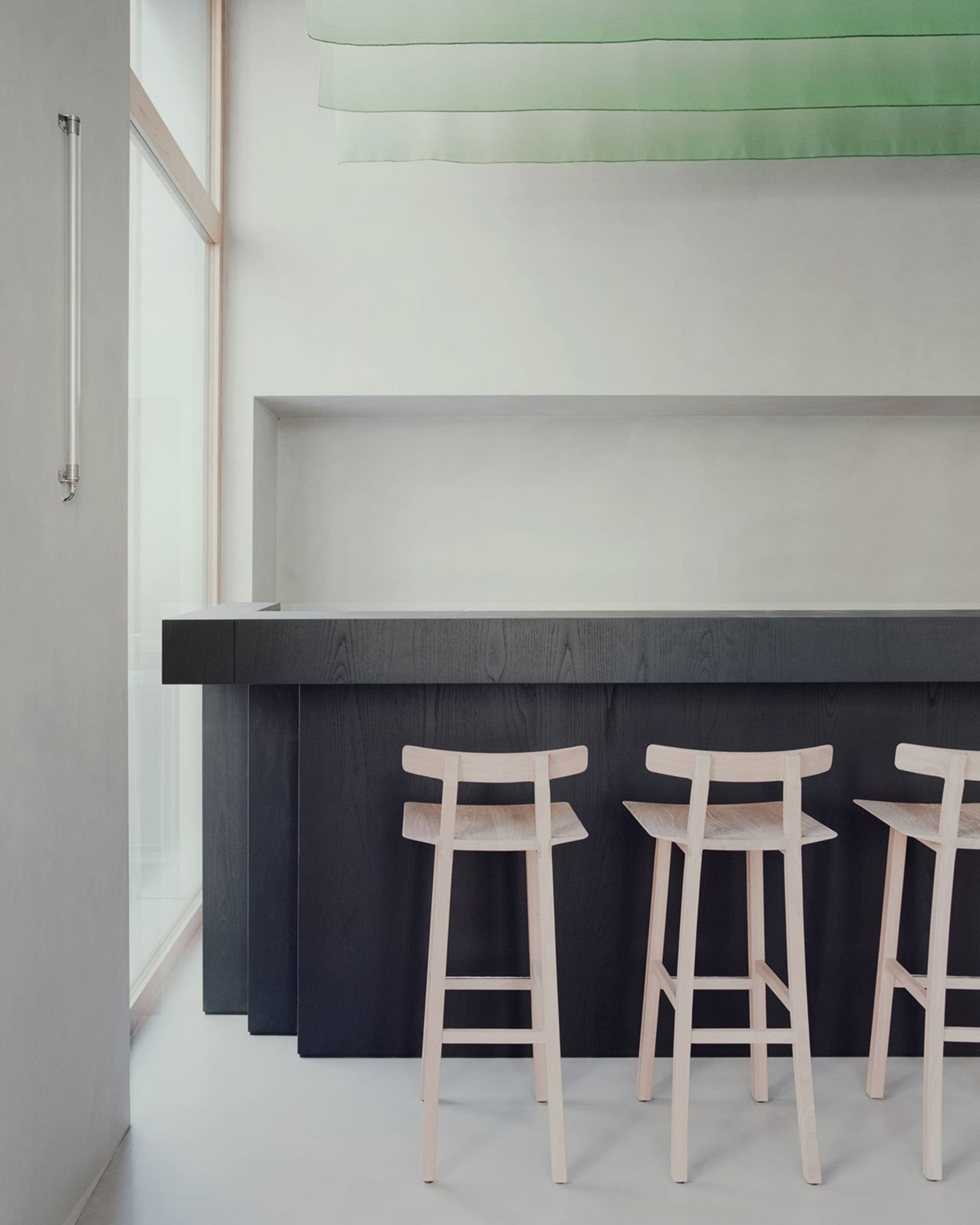 A modern bar counter with three stools in front, featuring a wooden counter and metal stools in a sleek design