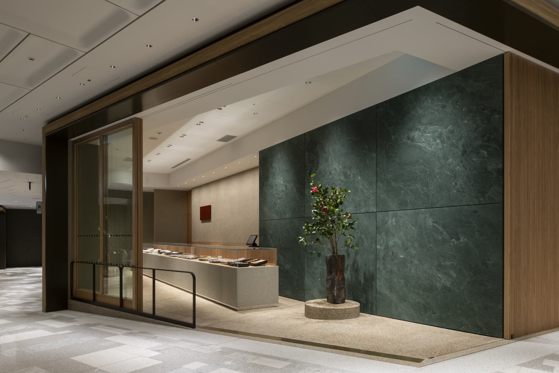 Lobby area with marble and green stone walls, a potted plant, and vases, creating an elegant and sophisticated atmosphere