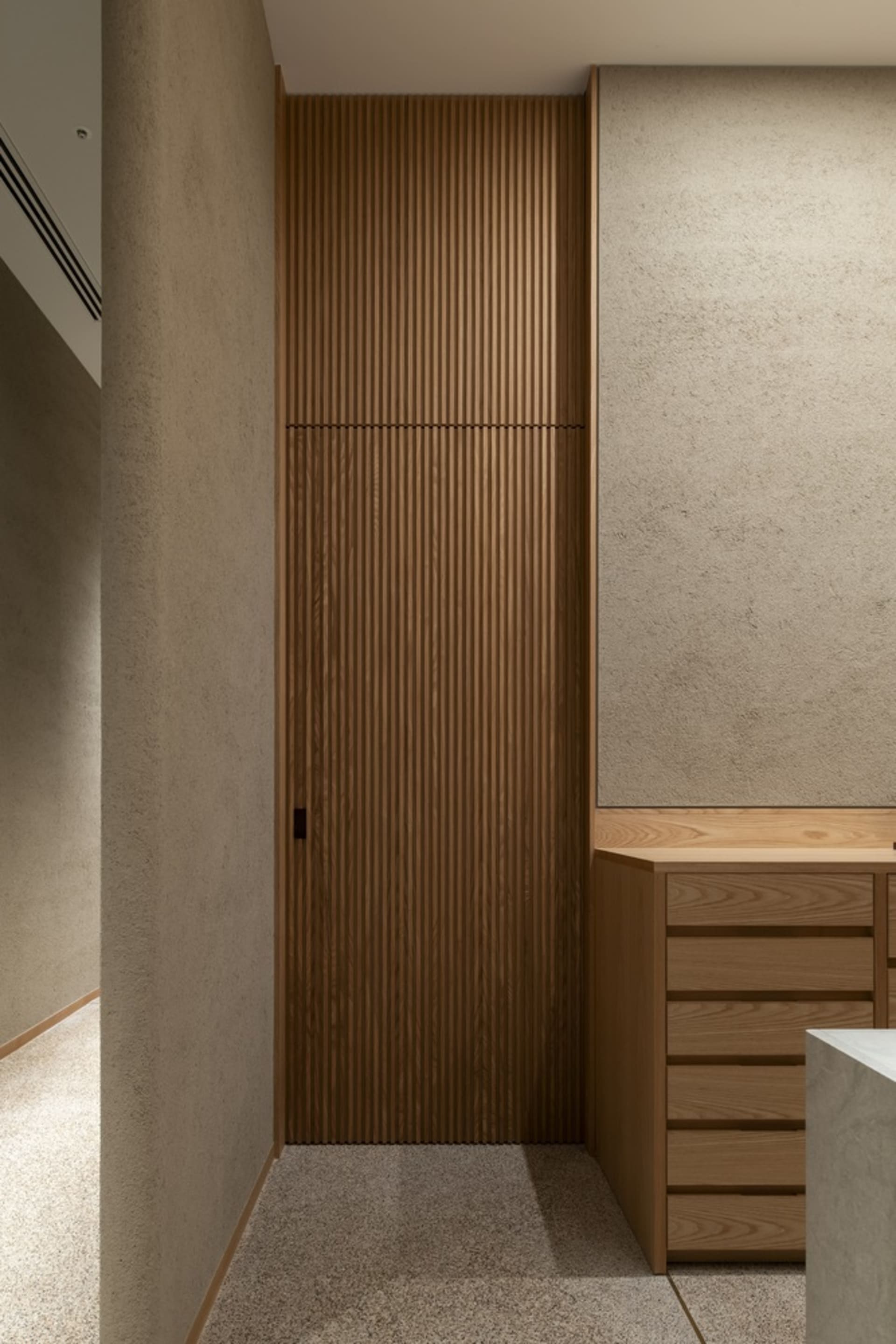 A wooden bathroom cabinet with a brown door, situated next to a wall in a warm and cozy bathroom setting