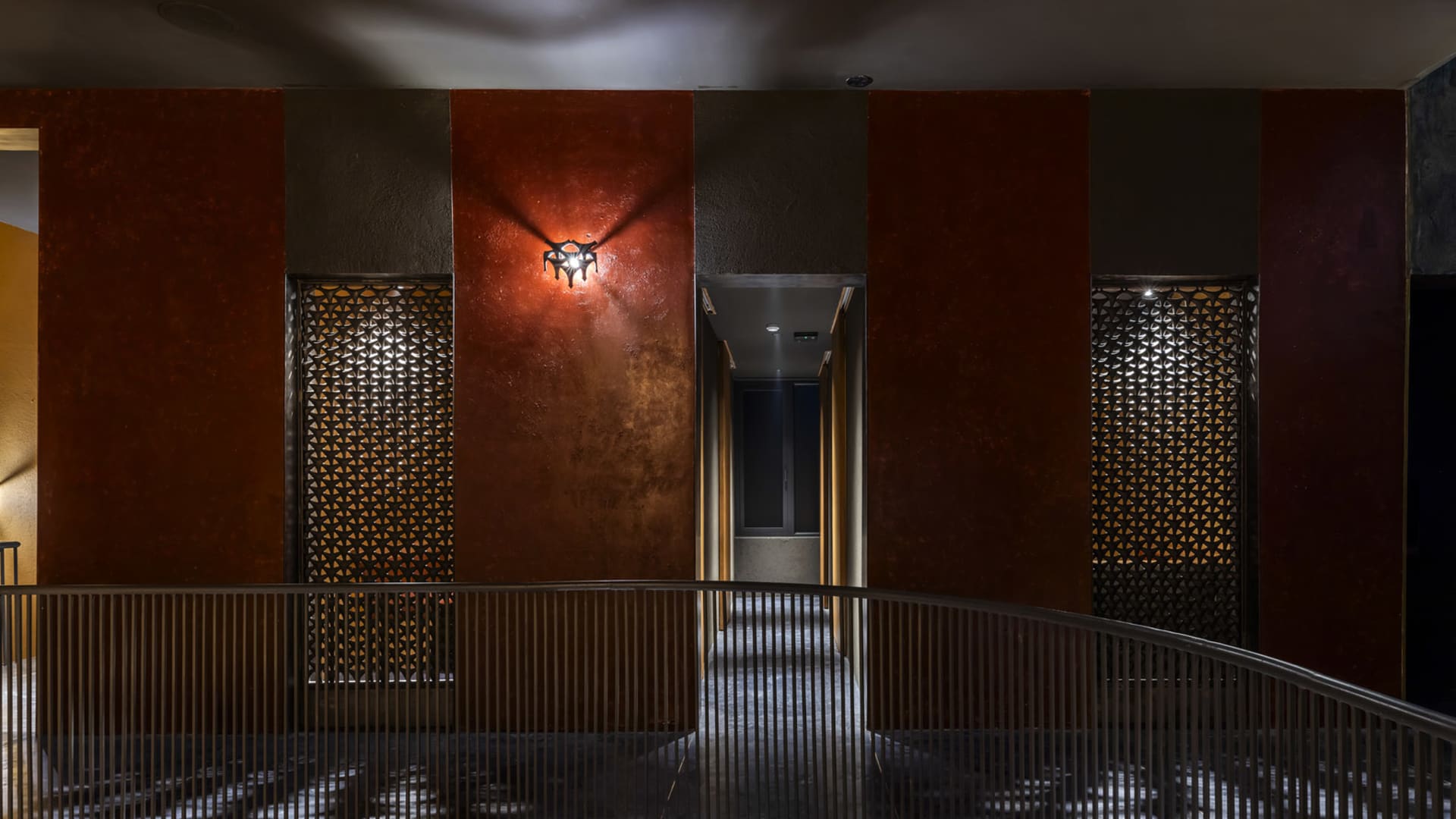 Narrow interior hallway with red walls, brown doors, and a textured brick or stone appearance