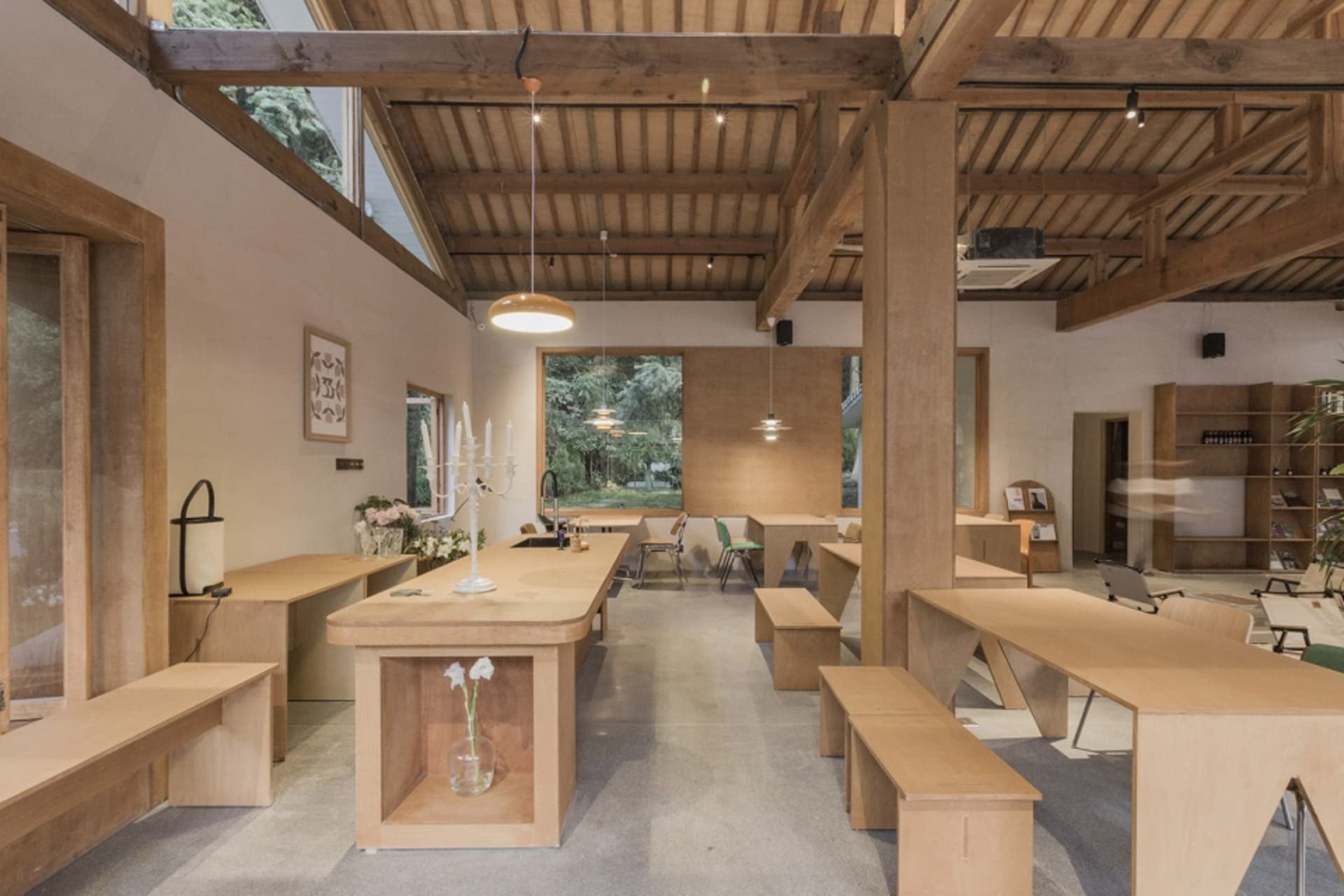 Warm and inviting open concept living area with a large wooden dining table, multiple chairs, and benches, featuring decorative vases and ample seating options