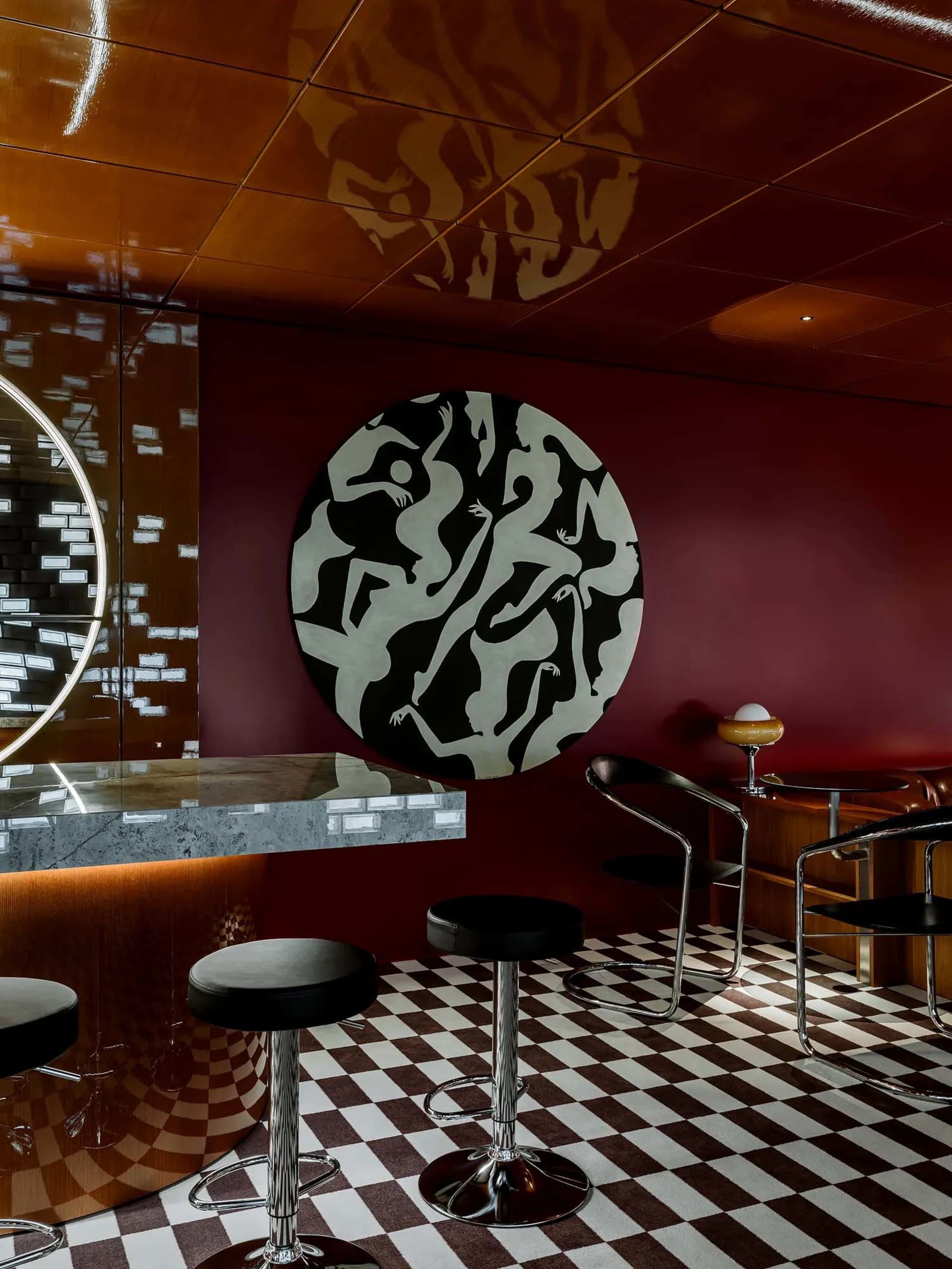 Modern bar area with a circular countertop, stools, and two chairs, creating a stylish and functional space