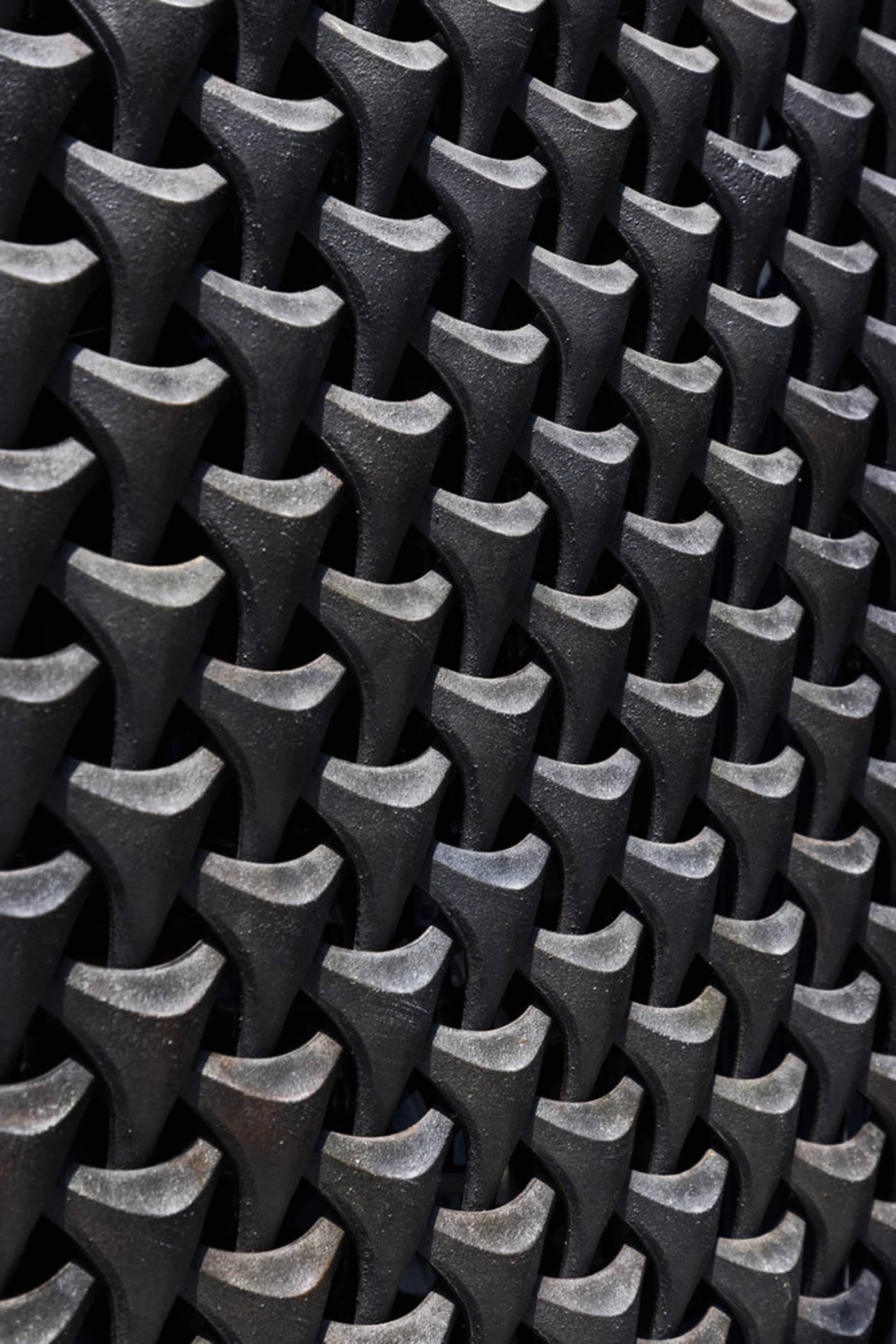 A modern indoor space with a black metal design resembling a brick wall or patterned floor, featuring a combination of materials and patterns, with black metal dominating the scene, and possible hints of gray or silver, in a well-lit environment