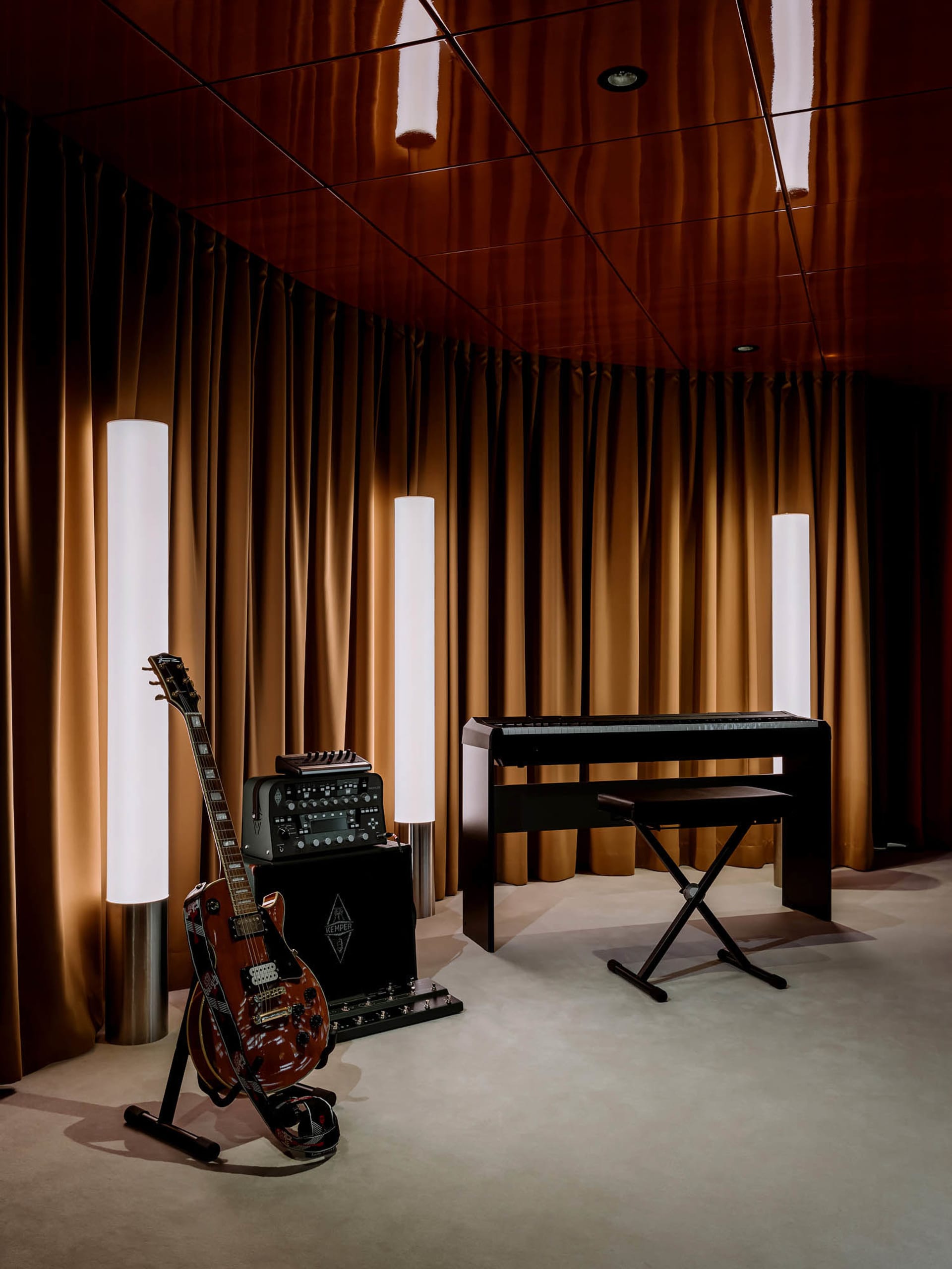 A dimly lit room with a piano and two guitars, creating a cozy atmosphere