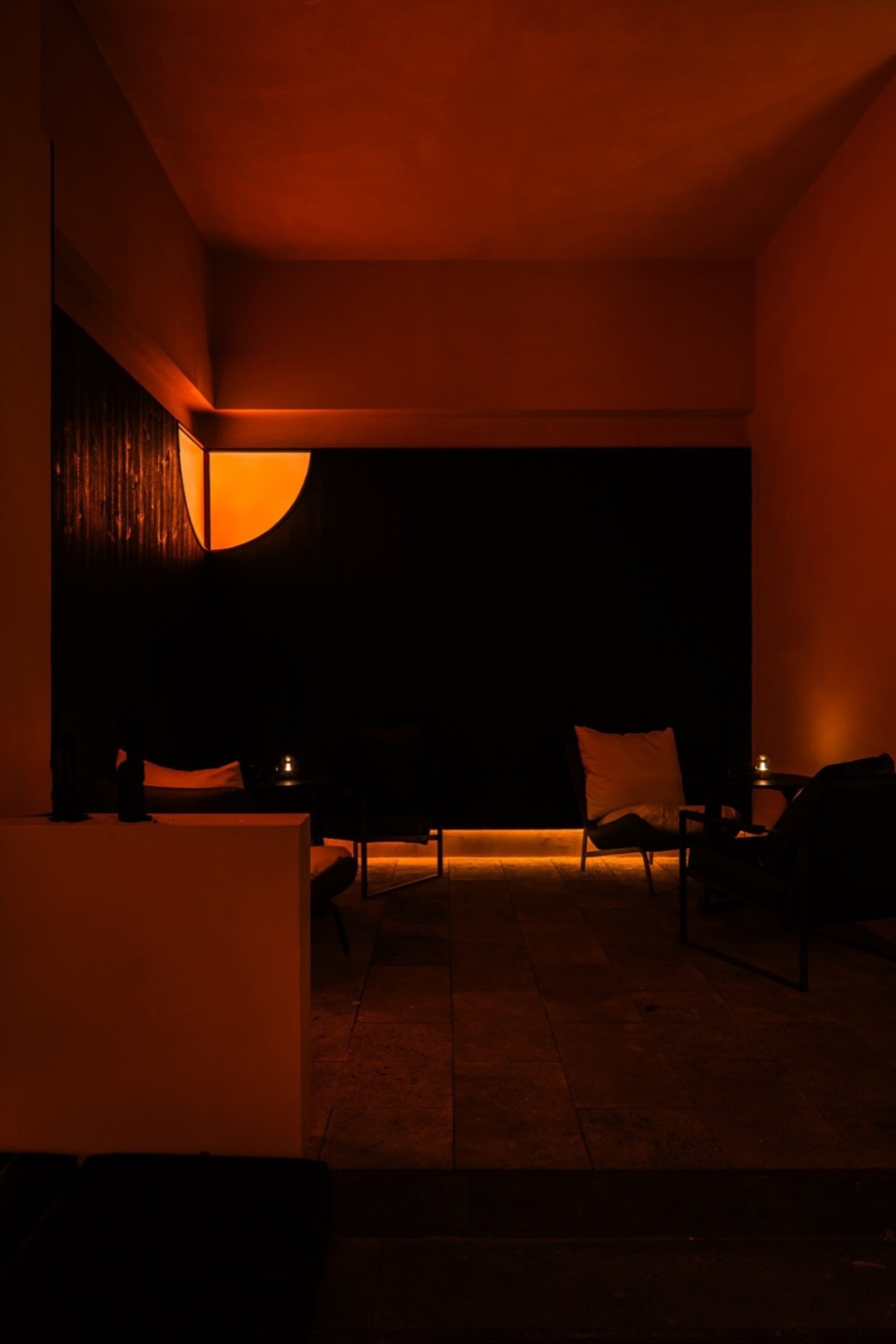 Cozy restaurant space with an orange-lit room, black walls, and a dining table with chairs and decorative items