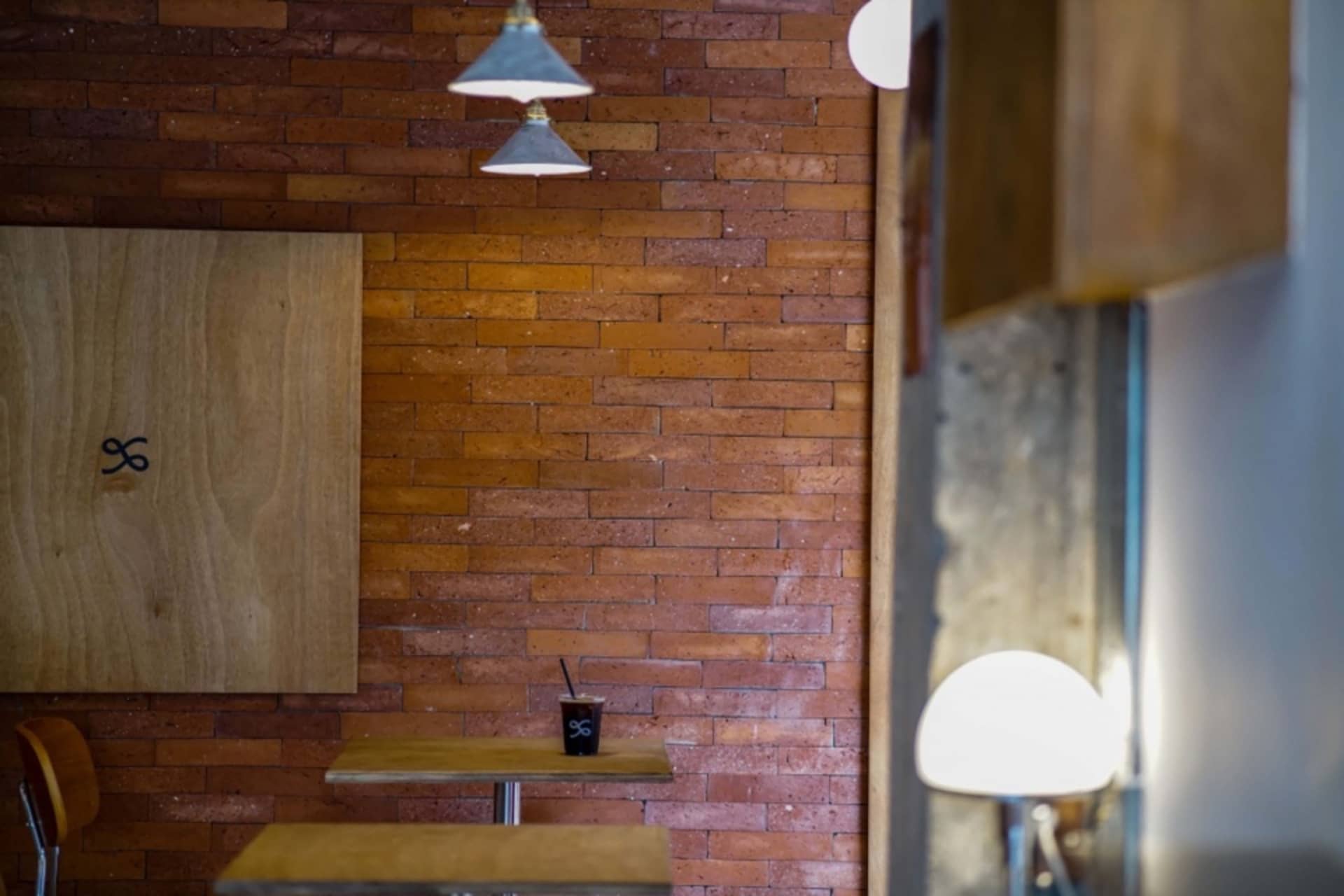 Warm and inviting restaurant interior with a brick wall, wooden table, and chairs, well-lit by natural light