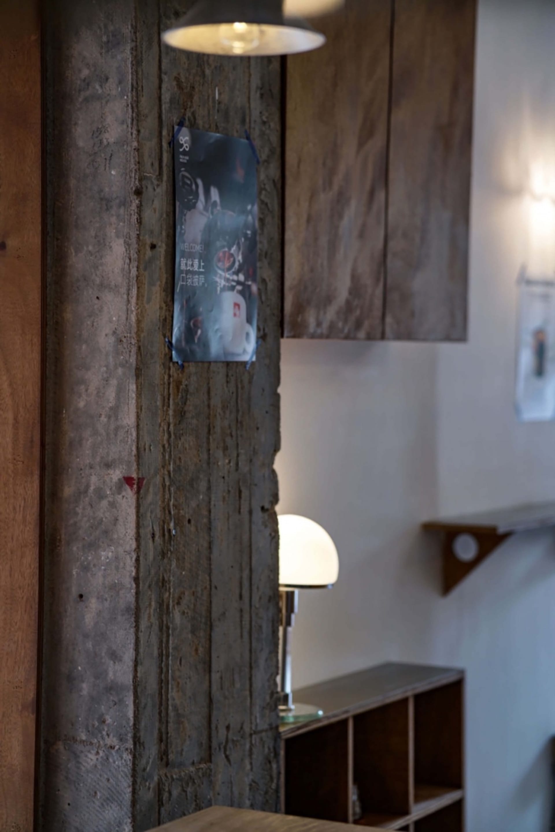 Cozy living and dining space with a wooden wall, lamp, posters, and a dining table