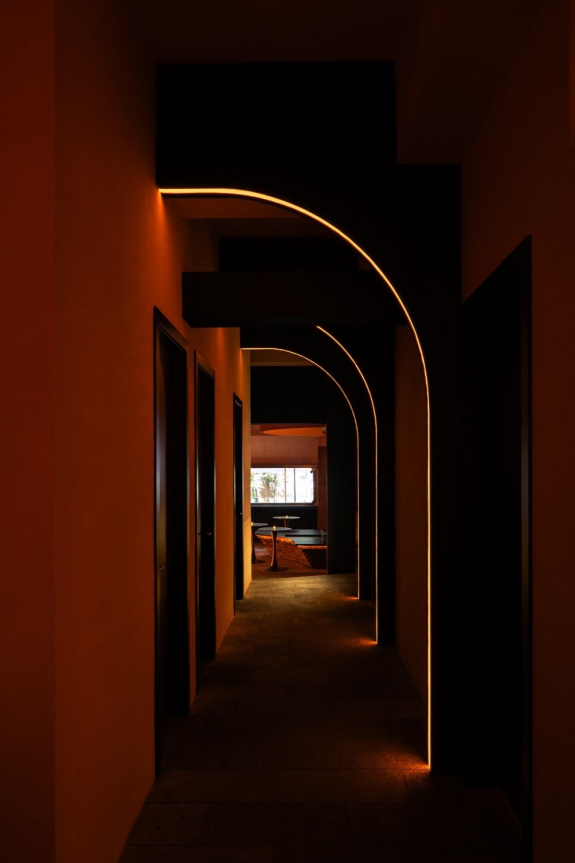 Dimly lit corridor with modern minimalist furniture, including benches and a dining table, in a building interior