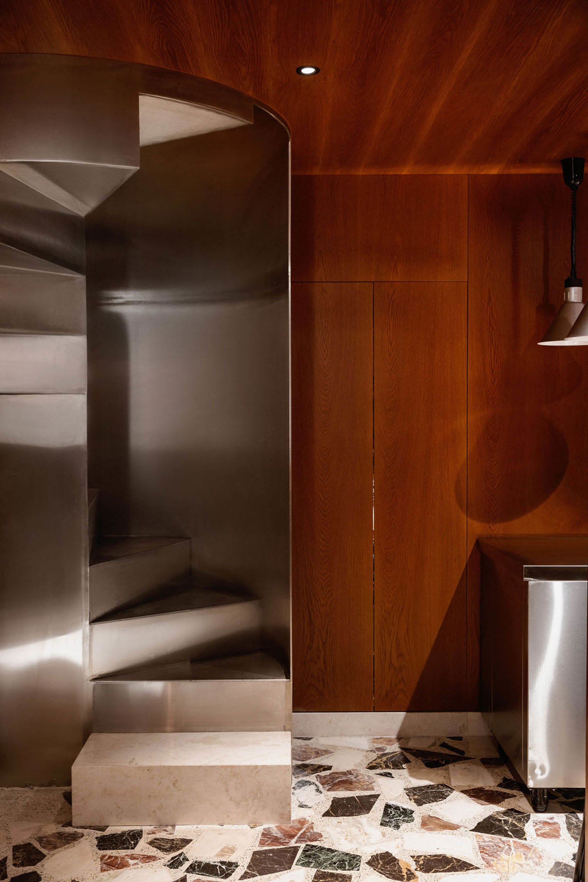 A modern interior design featuring a metal staircase leading to a wooden door, with a focus on functionality and simplicity