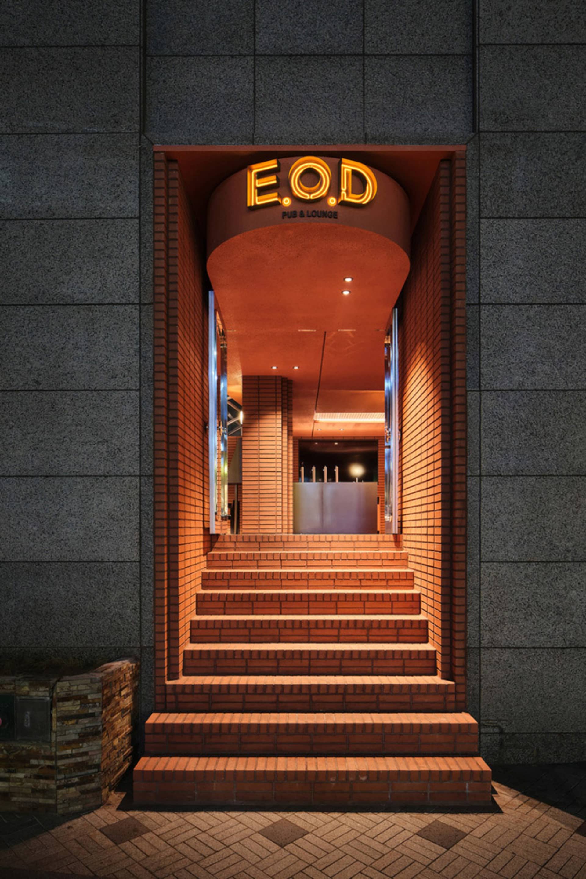 A warm and inviting orange brick building with a large archway entrance and stairs leading to another level