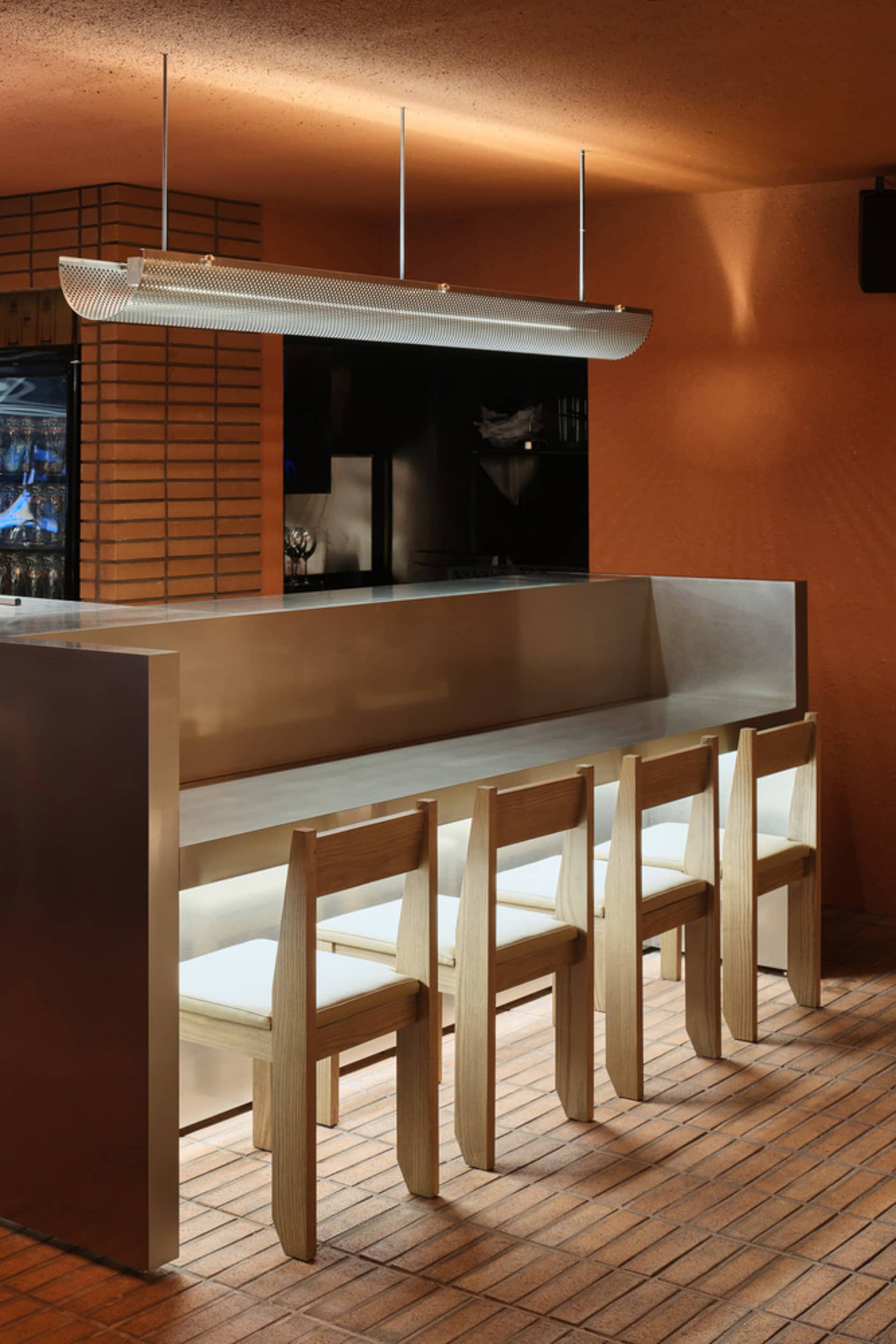 Modern bar with a metallic countertop, stools, and four chairs, creating a comfortable seating area for customers