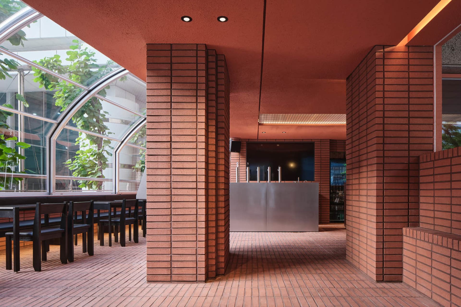 A cozy restaurant interior with red brick walls, a tile floor, and a dining table surrounded by chairs and bottles