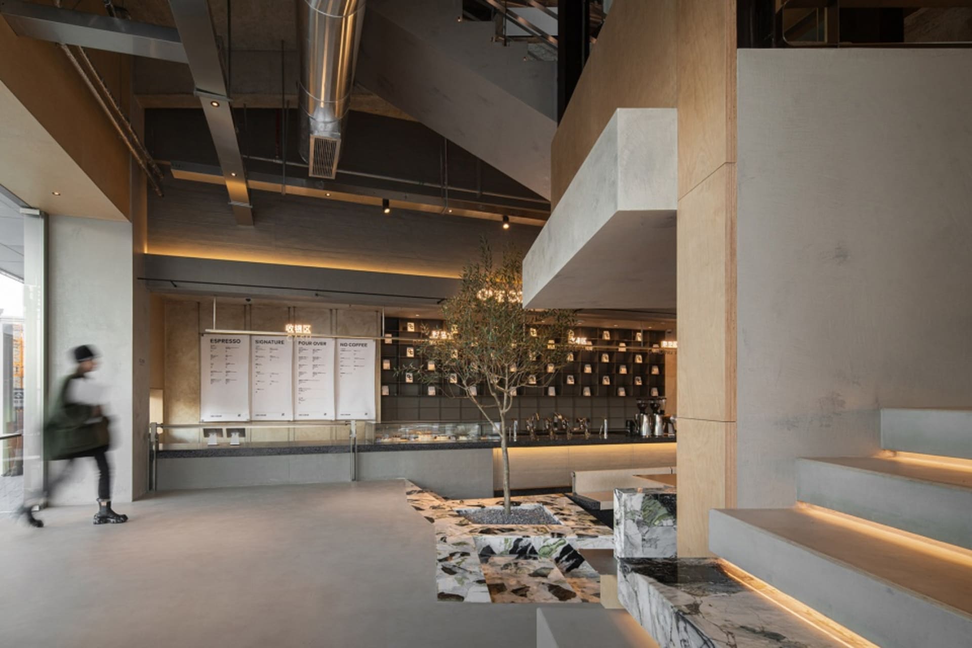 A modern cafe with a large open space, high ceilings, and comfortable seating areas with chairs and a dining table