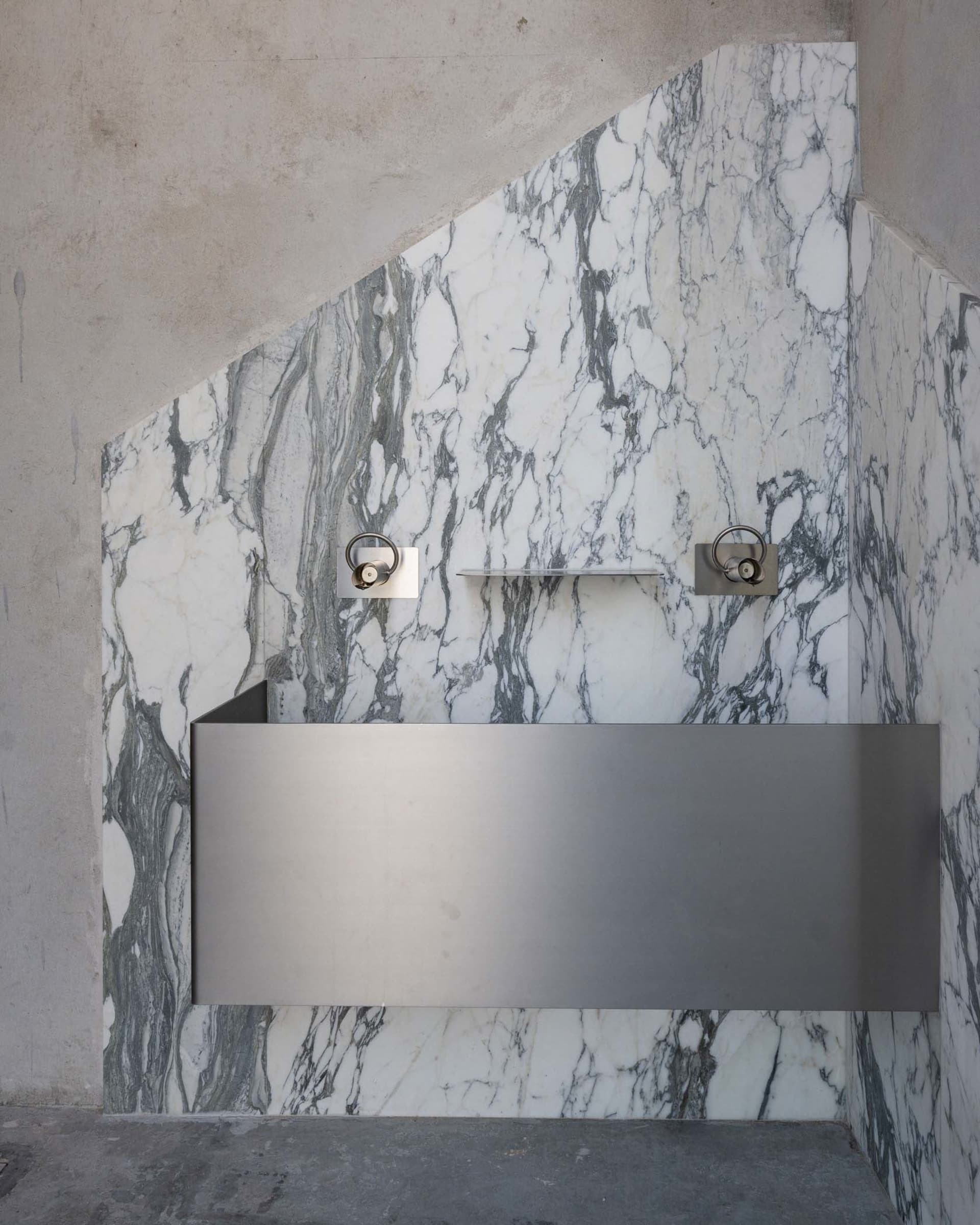 Luxurious marble bathroom with a metal sink, large mirror, and warm lighting
