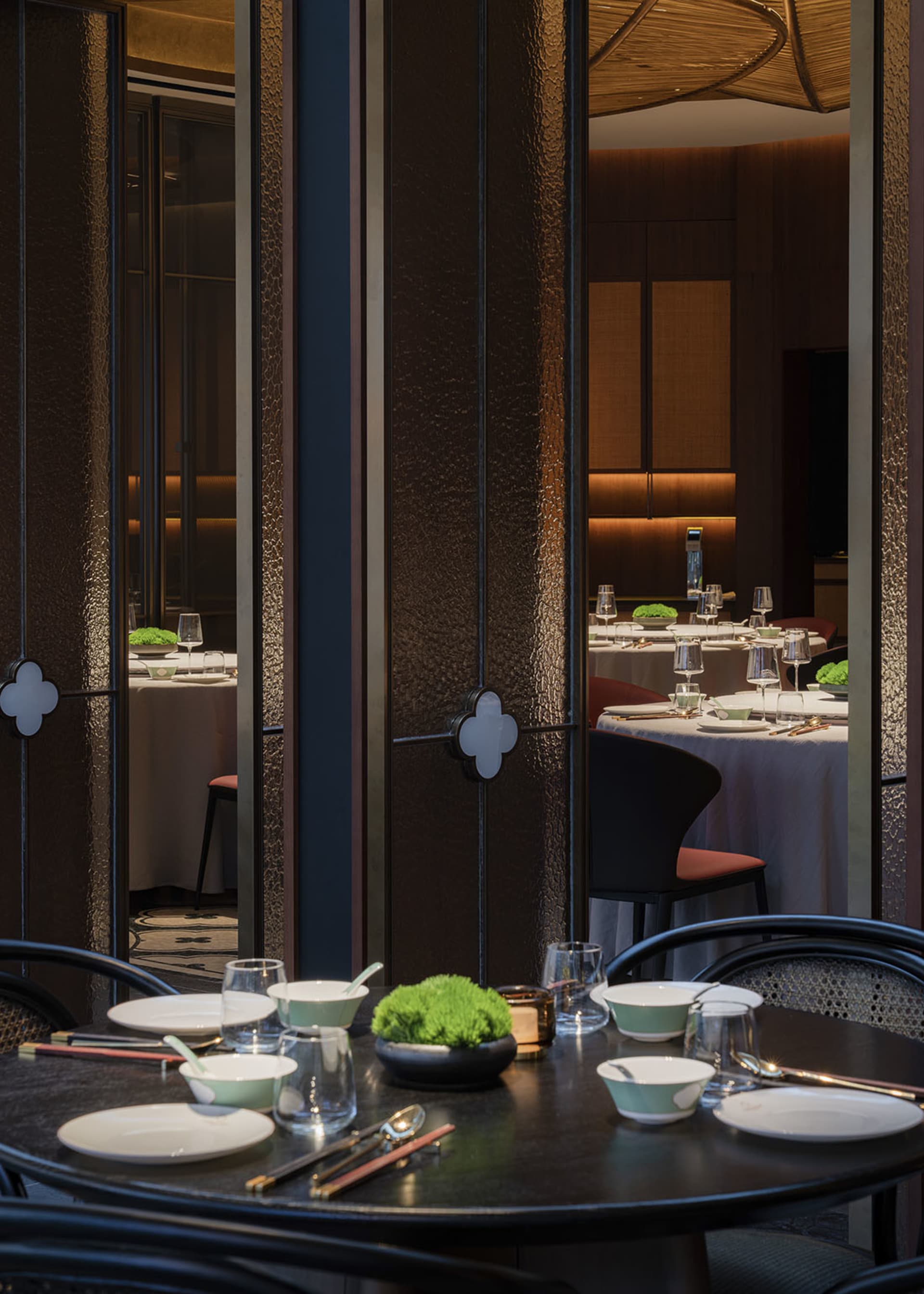 Dimly lit dining space with modern tables, chairs, and tableware, creating a cozy atmosphere