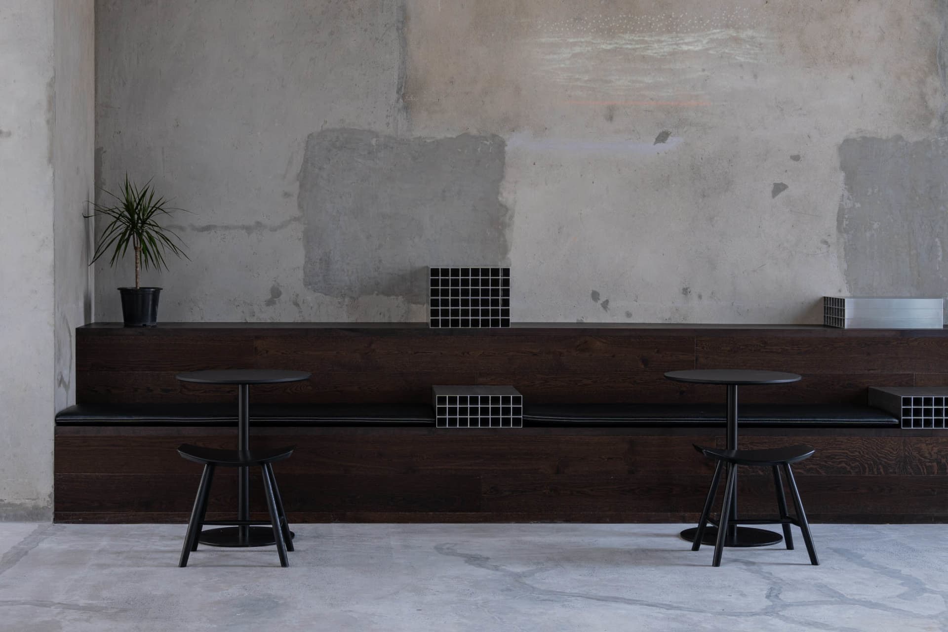 A restaurant interior with a wooden dining table, black chairs, and brick-patterned walls, creating a stylish and comfortable atmosphere for dining and socializing